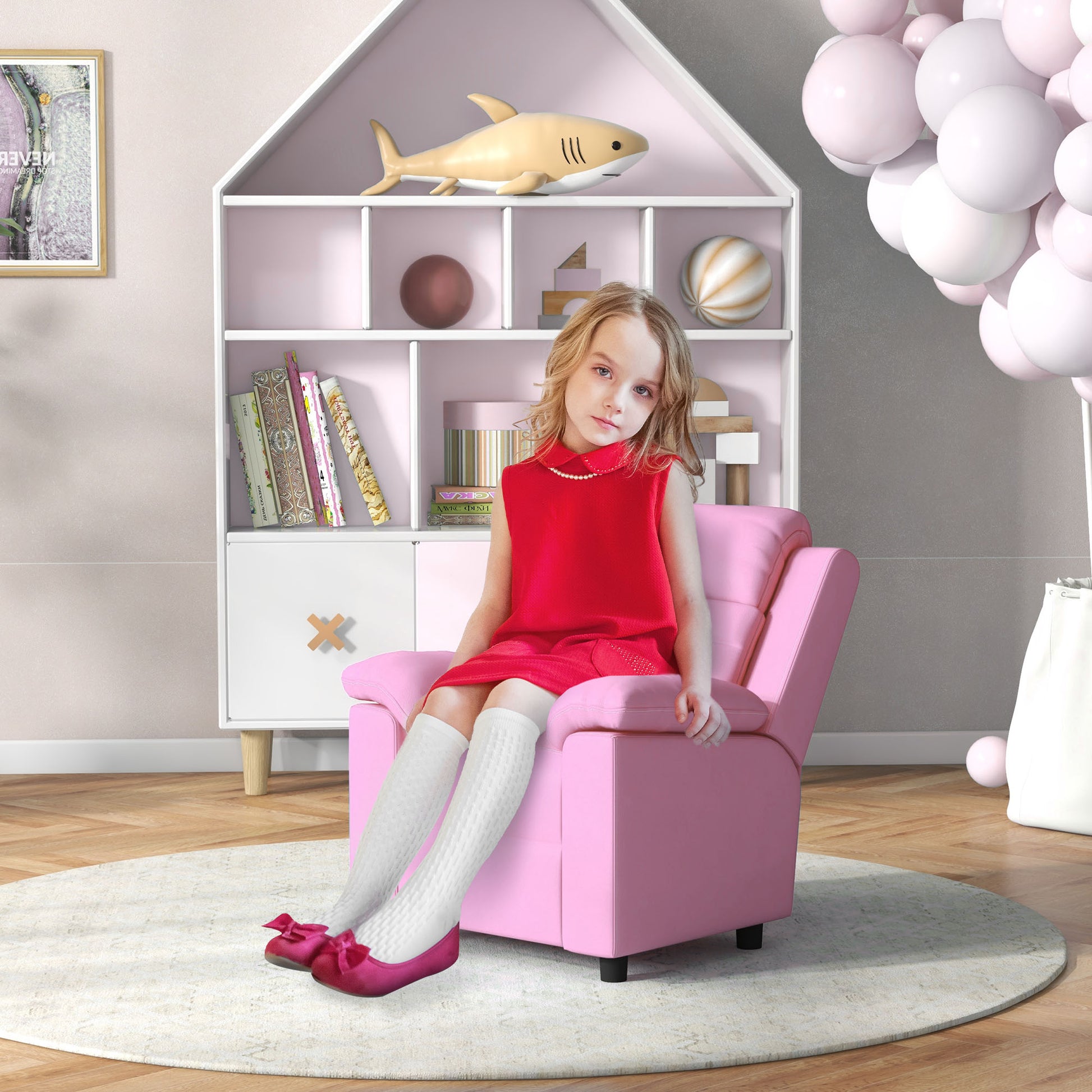 Girl in red dress sitting on pink kids armchair wearing white kneehigh socks and pink ballet flats