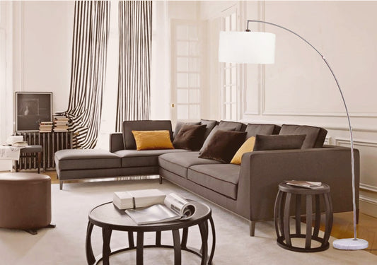 Modern arc floor lamp with white drum shade over sectional sofa