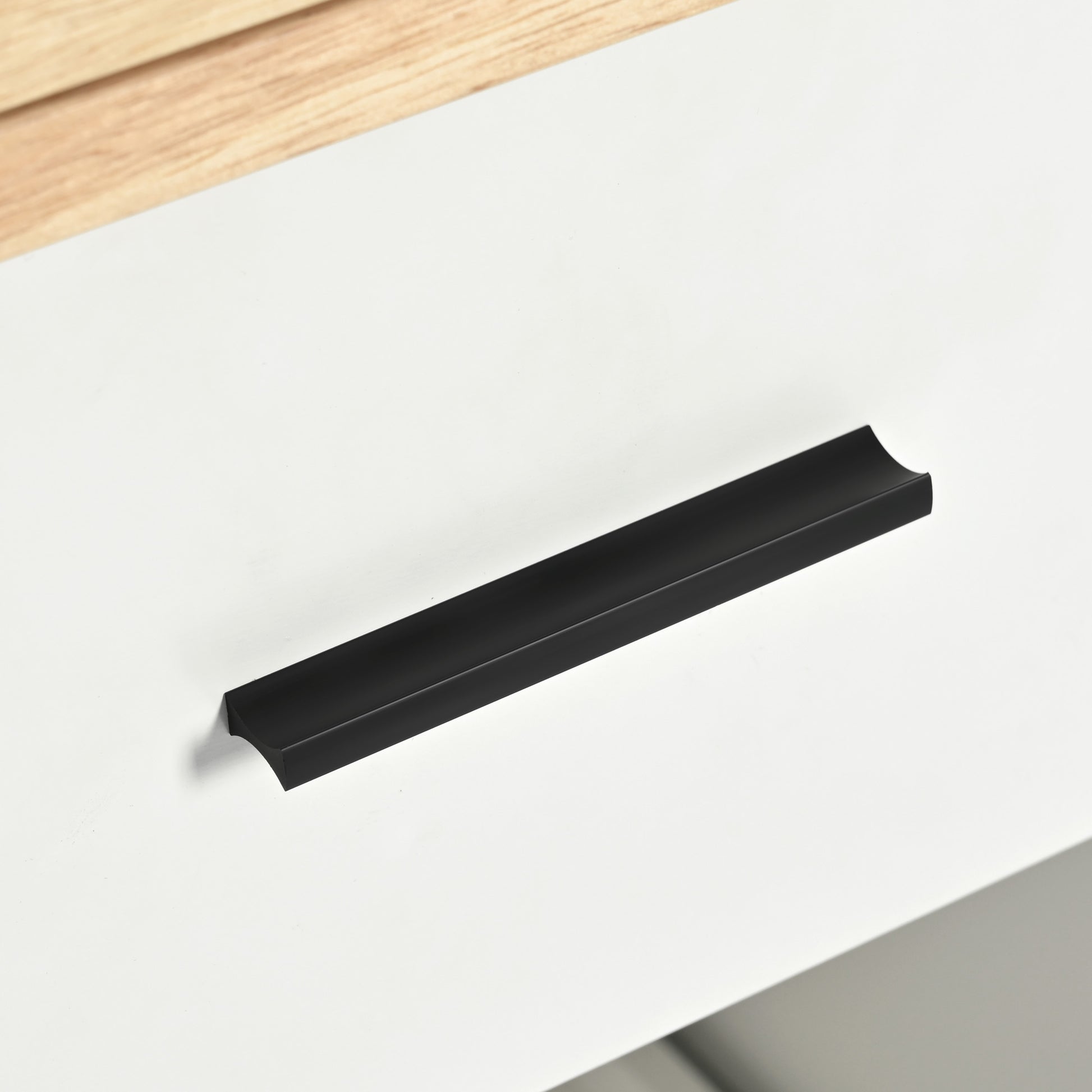 Matte black modern edge pull cabinet handle on white surface