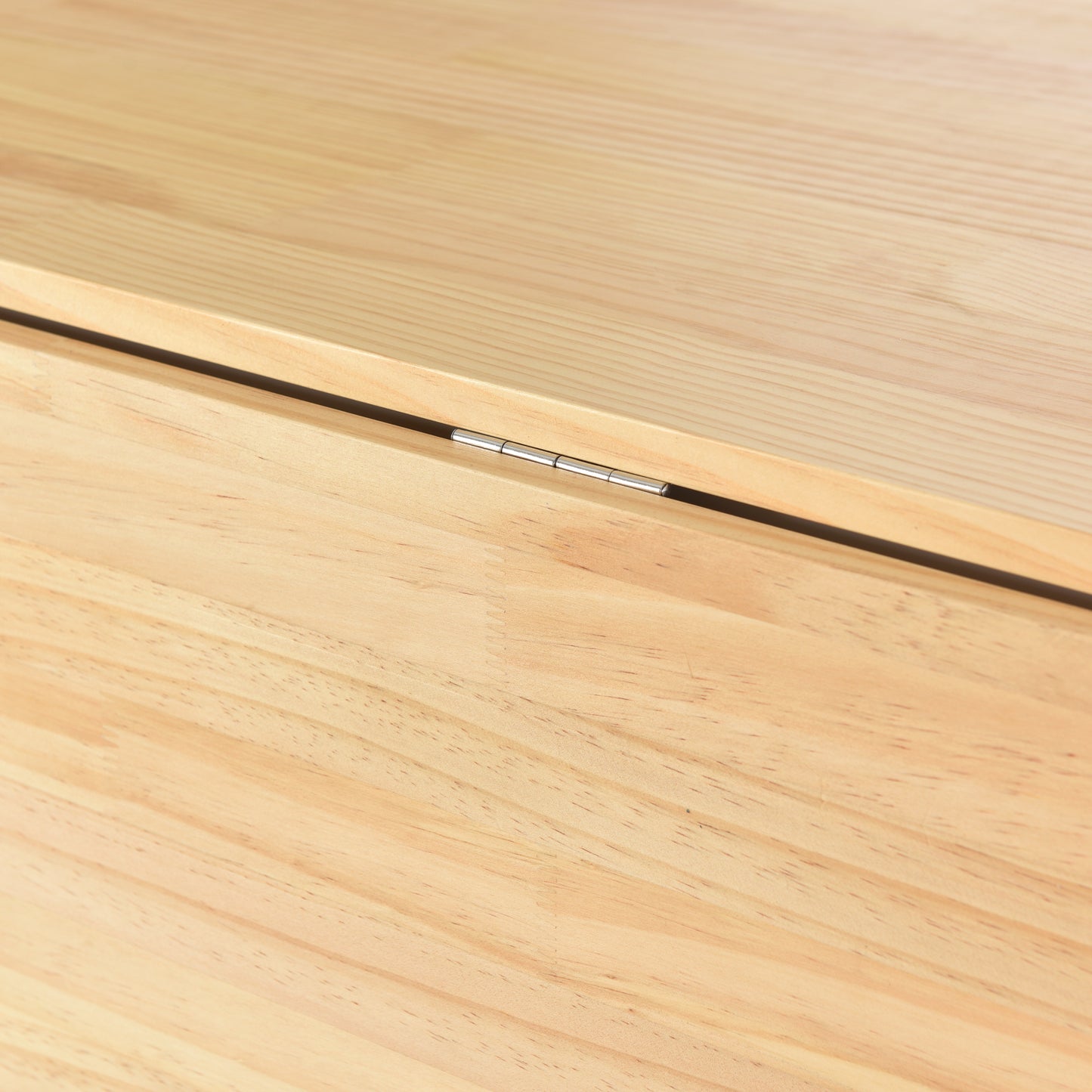 Closeup of a natural wood tabletop with visible grain and a silver hinge
