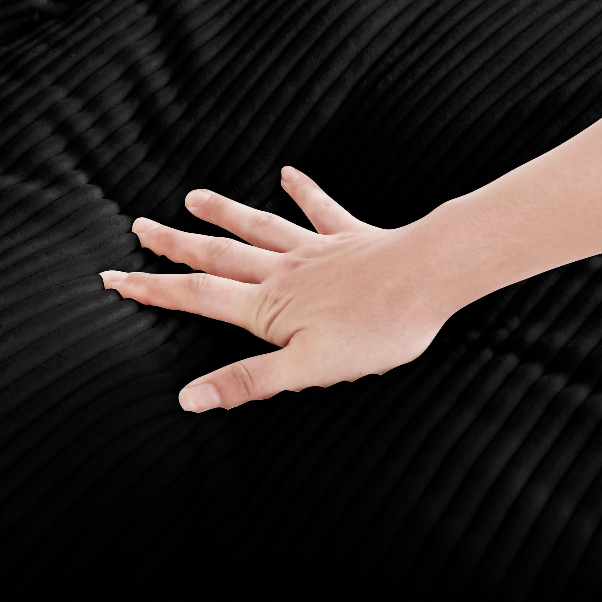 Closeup of a hand pressing into plush black corduroy fabric showing texture