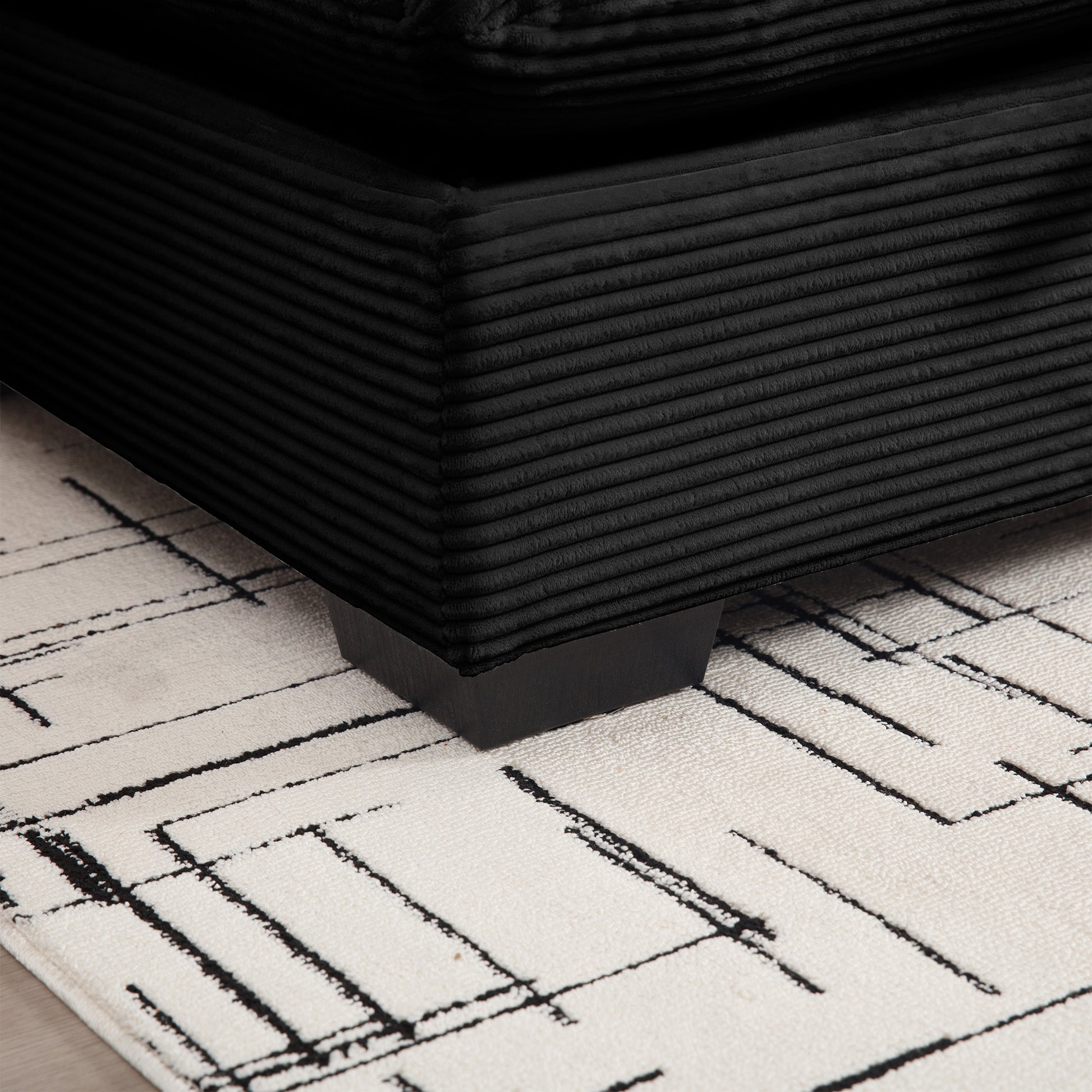 Black corduroy armchair corner with tufted texture on a cream rug