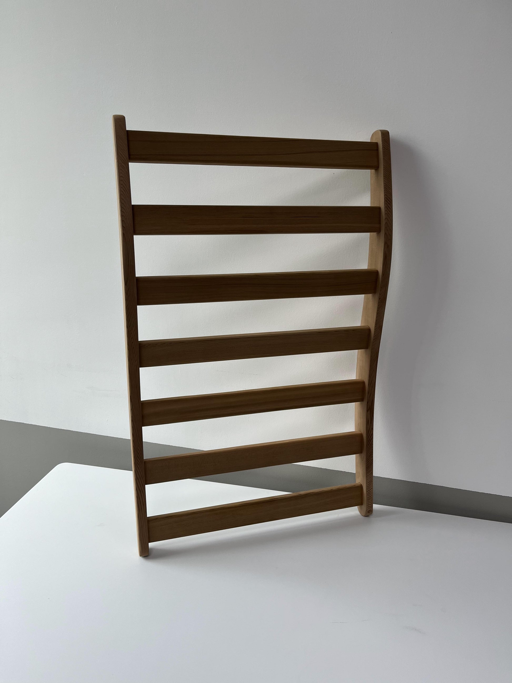 Natural wood wallmounted ladder shelf with seven horizontal rungs for display or storage