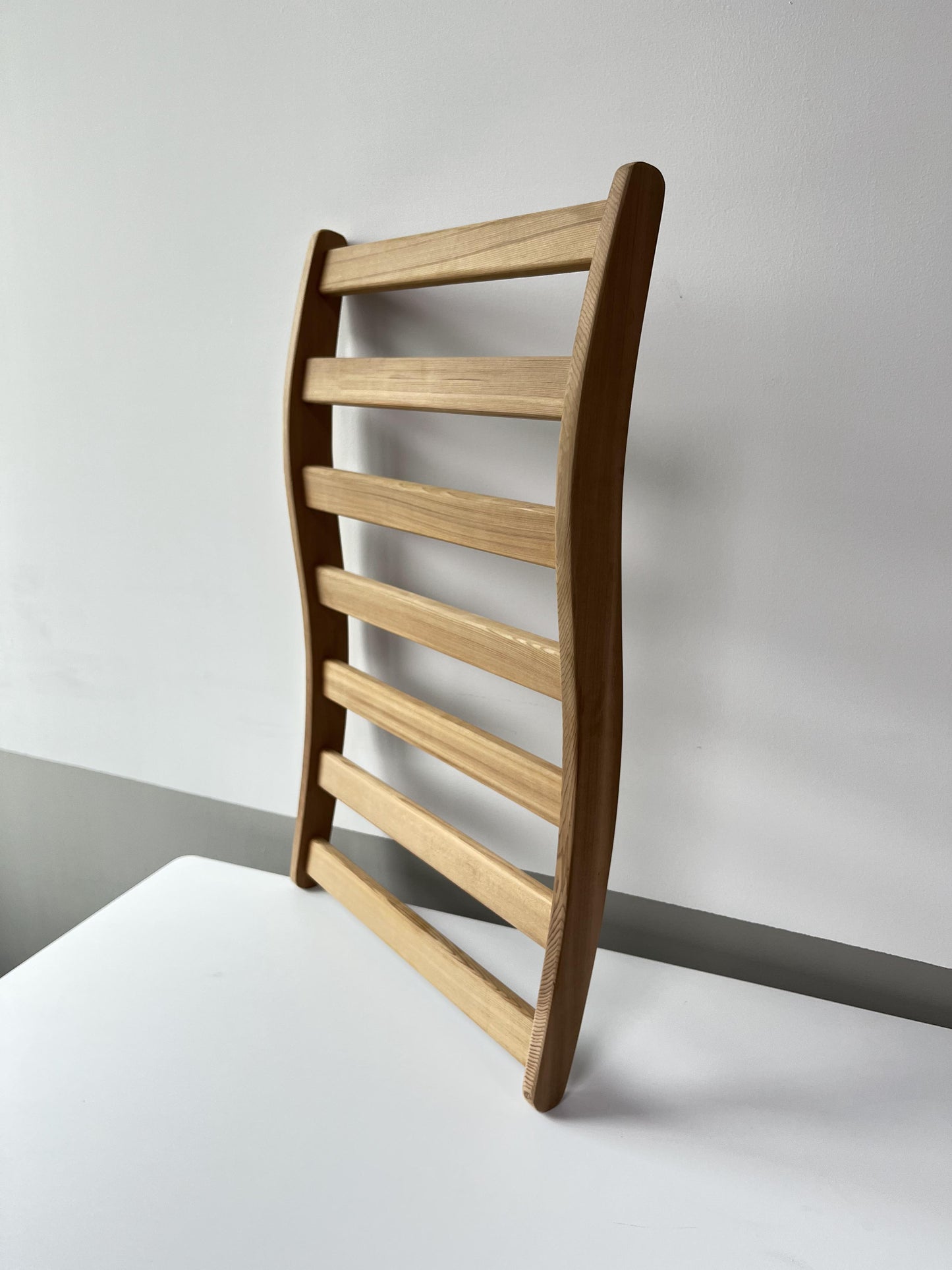 Curved modern wooden ladder shelf with five light oak shelves