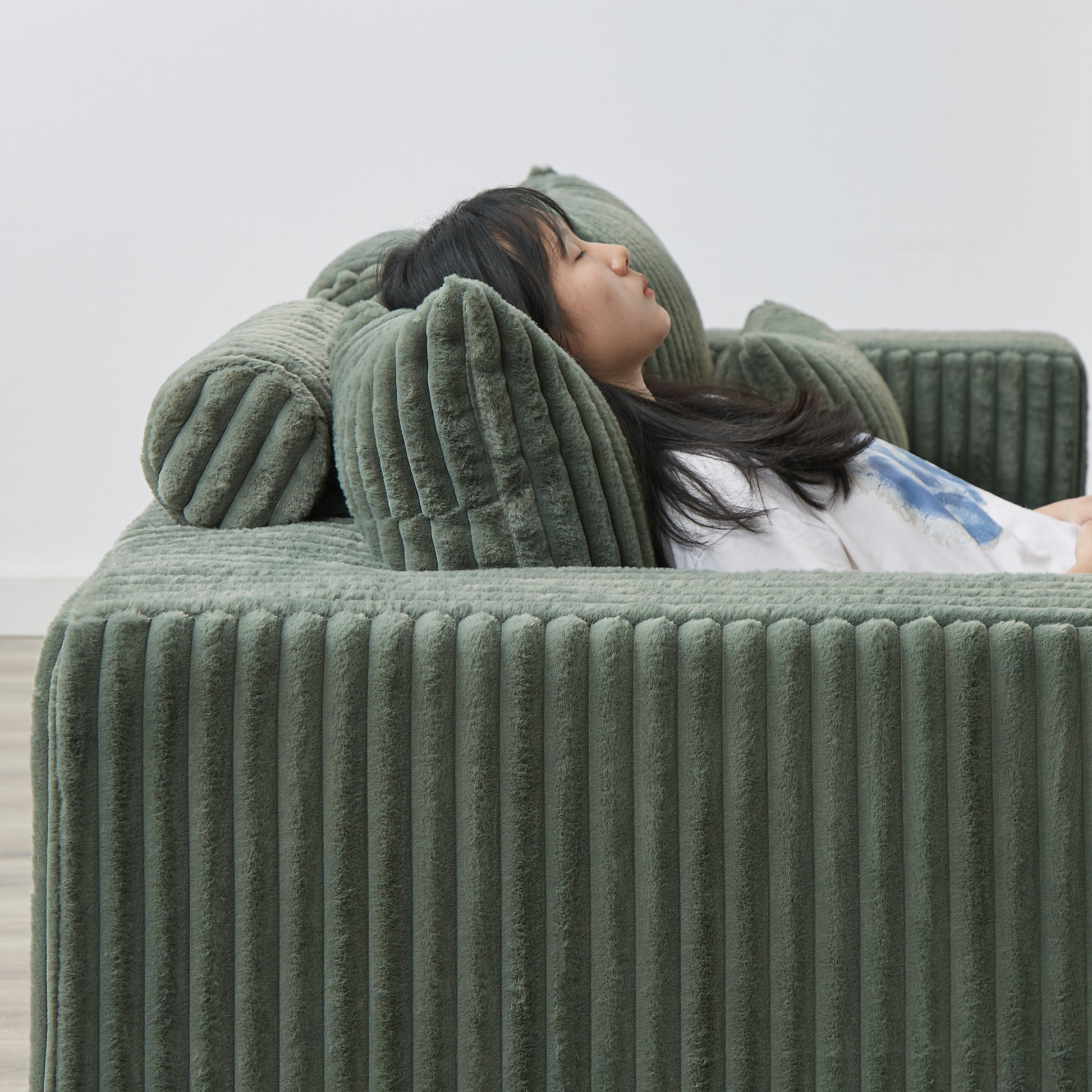 Cozy sage green corduroy sofa with plush pillows perfect for relaxation and lounging