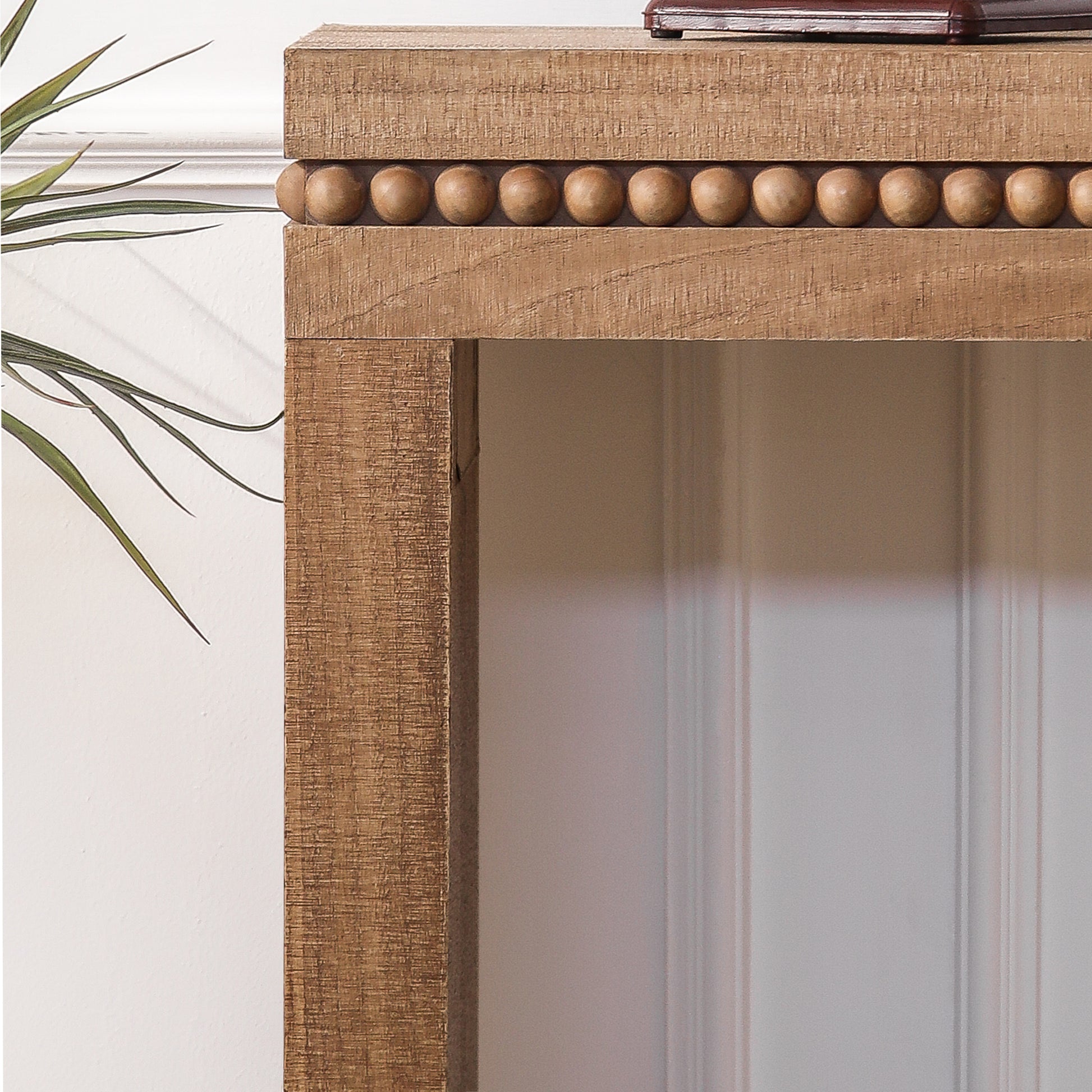 Closeup of a rustic wooden console table with beaded trim and textured finish