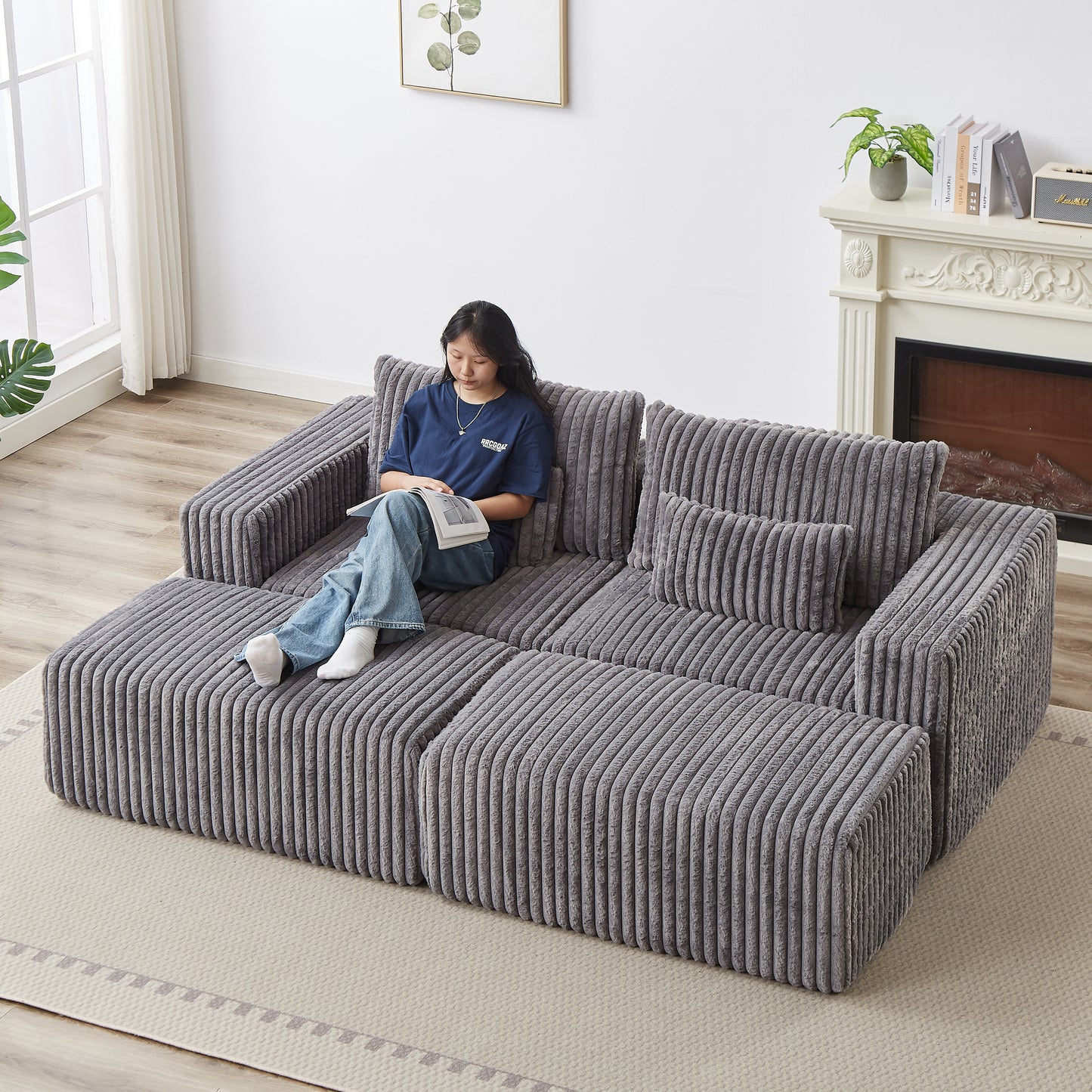 Gray corduroy modular sofa with plush cushions and a woman reading