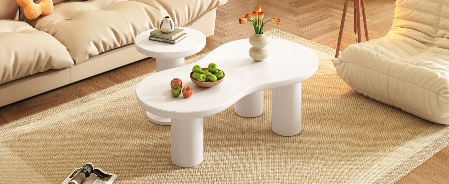Modern white oval coffee table with sculpted legs holding apples and a vase of flowers