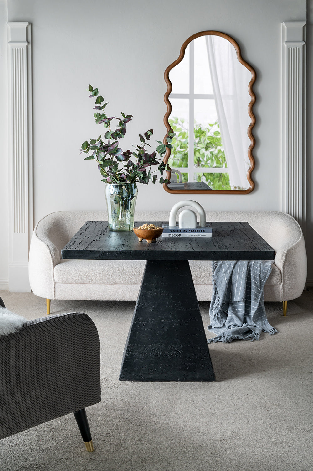 Dark textured wood dining table with sculptural base and modern decor accents