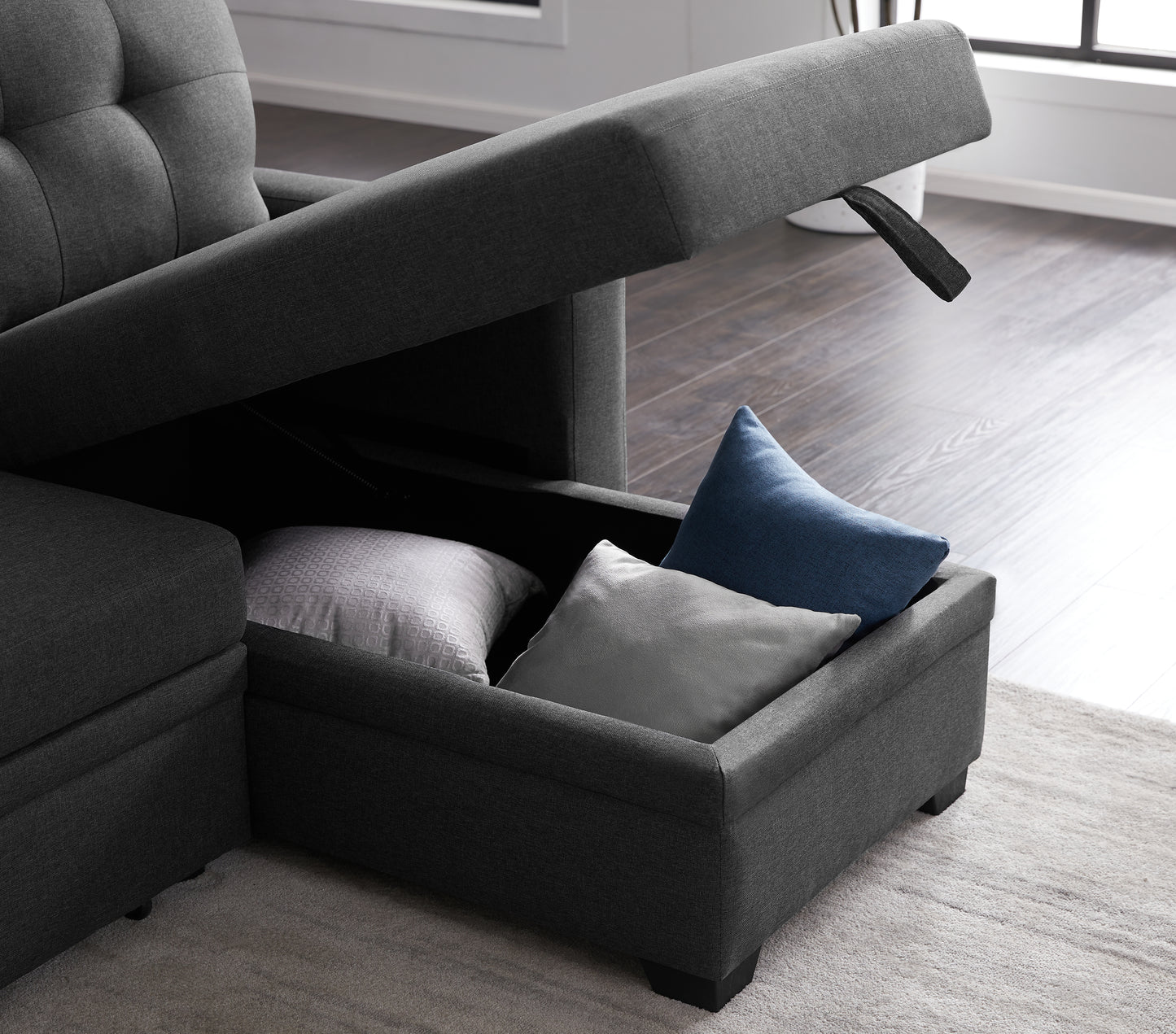 Dark gray sectional sofa with hidden storage compartment containing decorative pillows