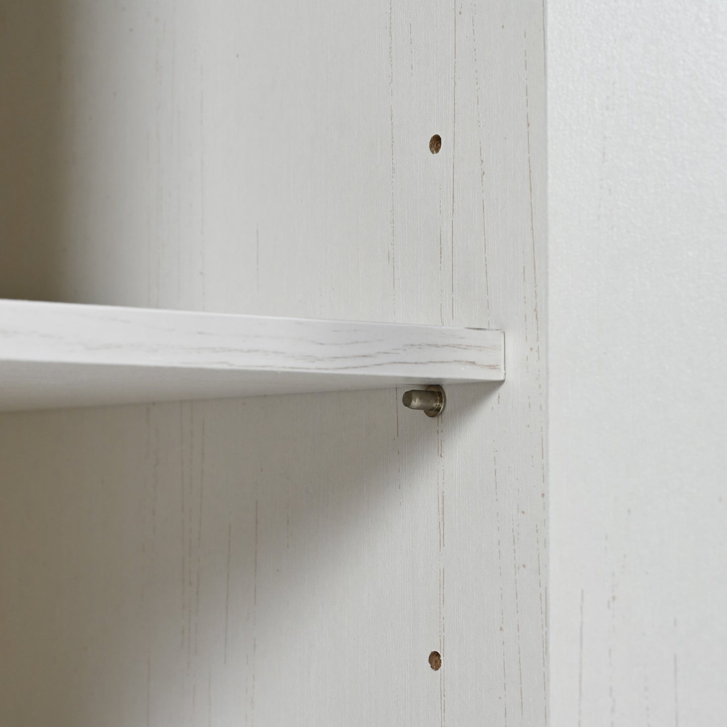 White particleboard shelf with metallic peg fastener detail