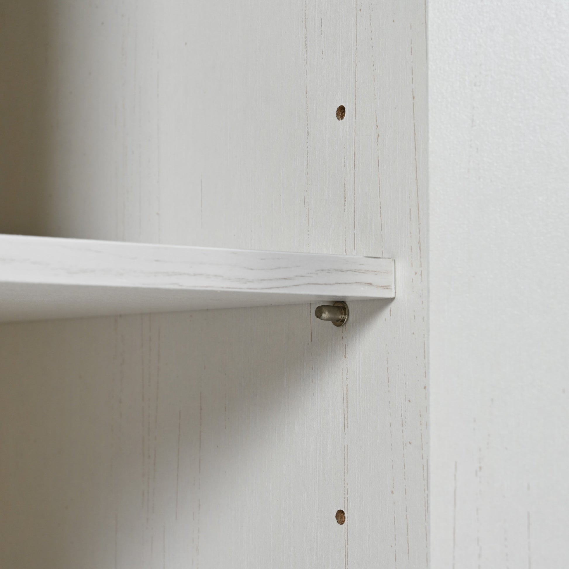 White particleboard shelf with metallic peg fastener detail