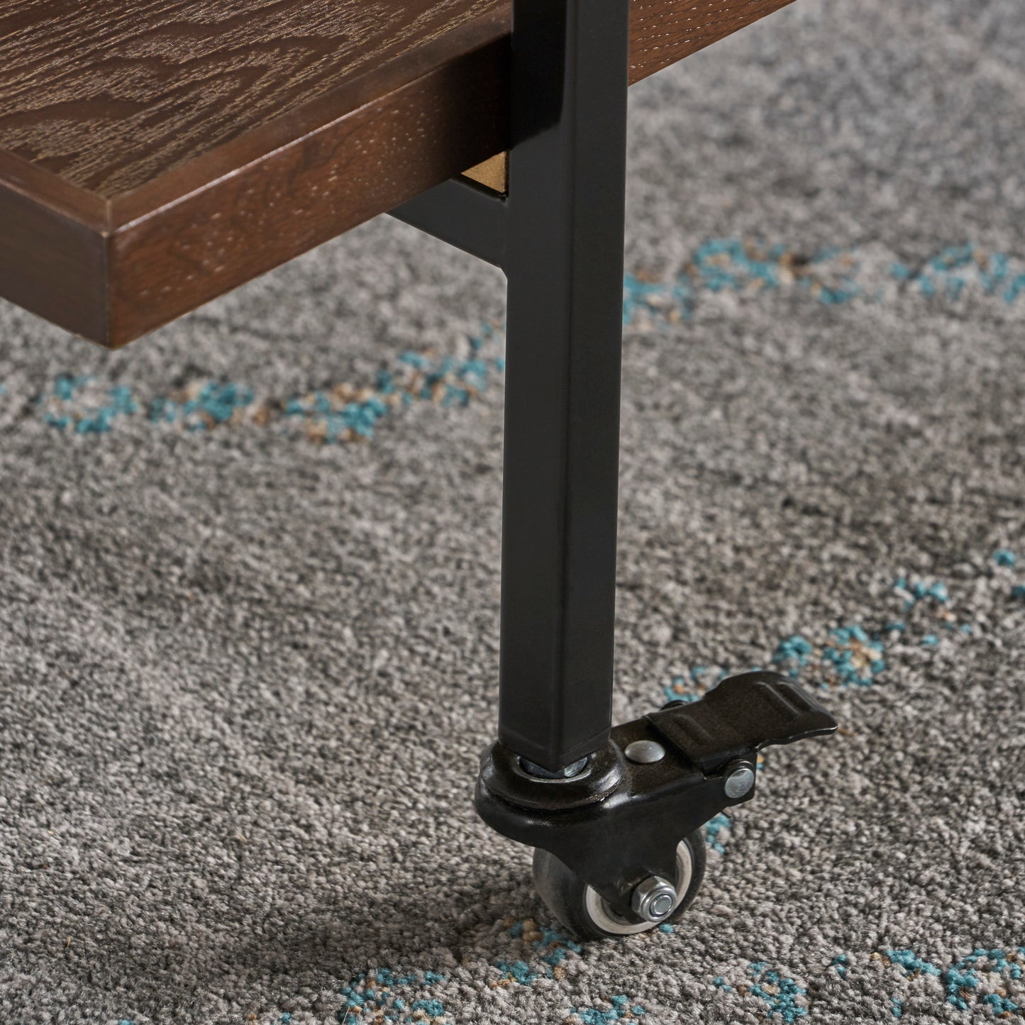 Closeup of a rolling caster wheel on a dark metal leg of a wooden shelf