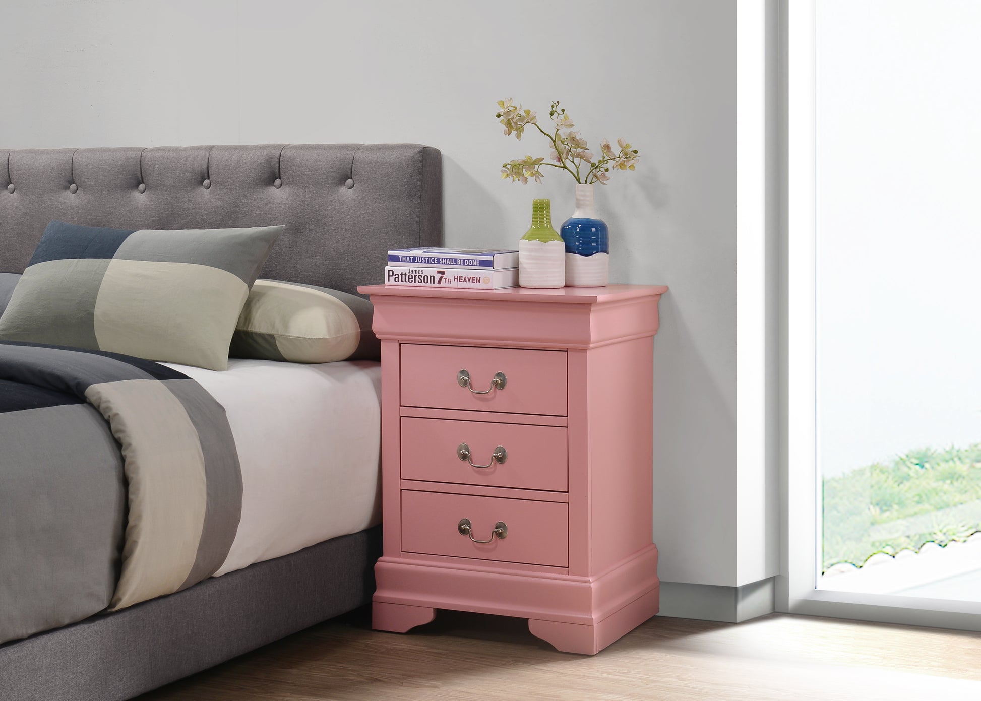 Dusty rose bedside table with three drawers and ornate hardware