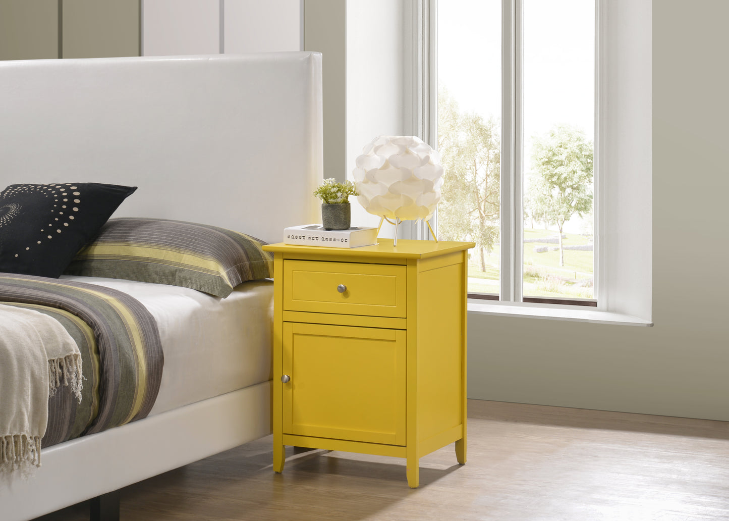 Yellow wooden nightstand with a drawer and cabinet next to a white bed
