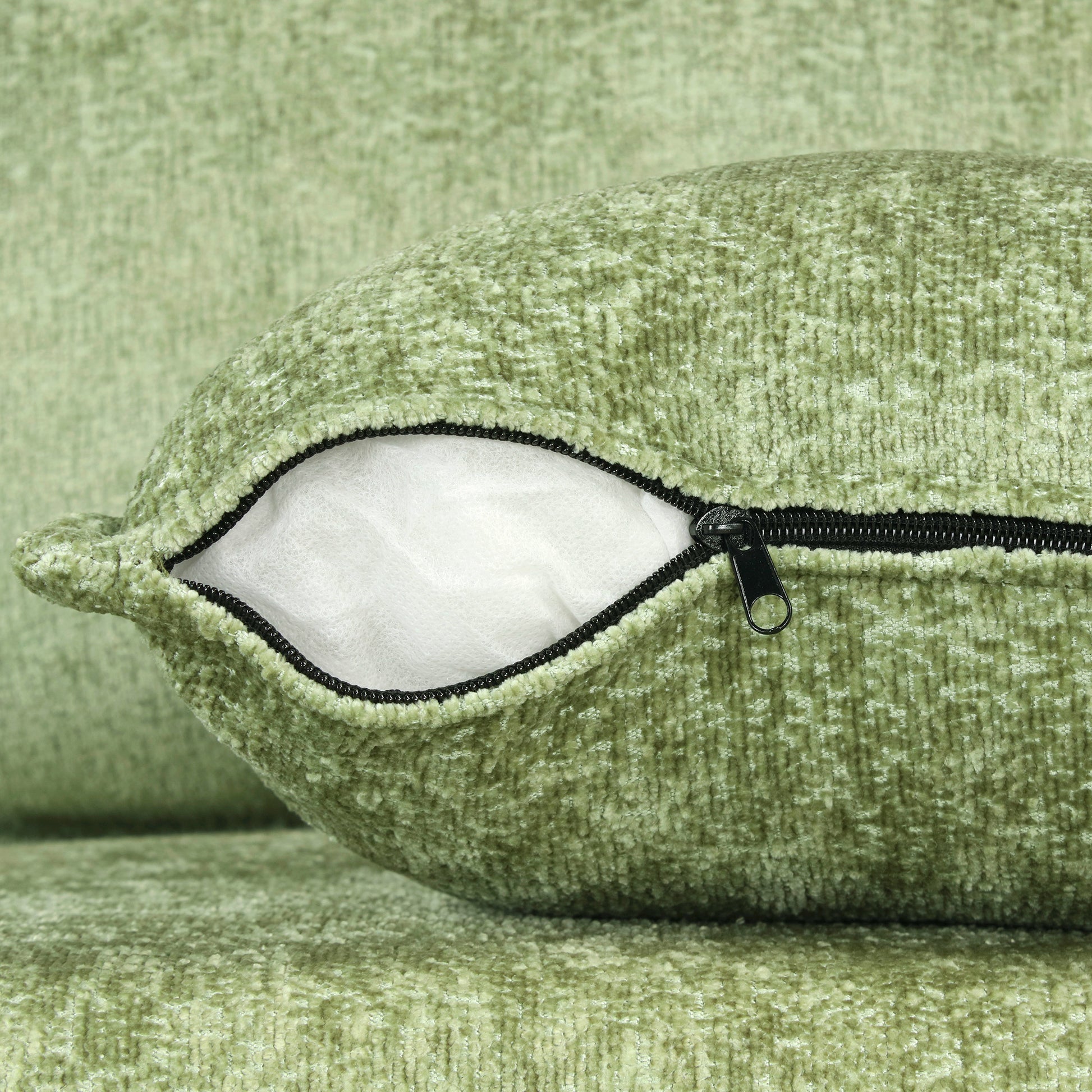 Closeup of a textured green throw pillow with an exposed zipper revealing its white filling