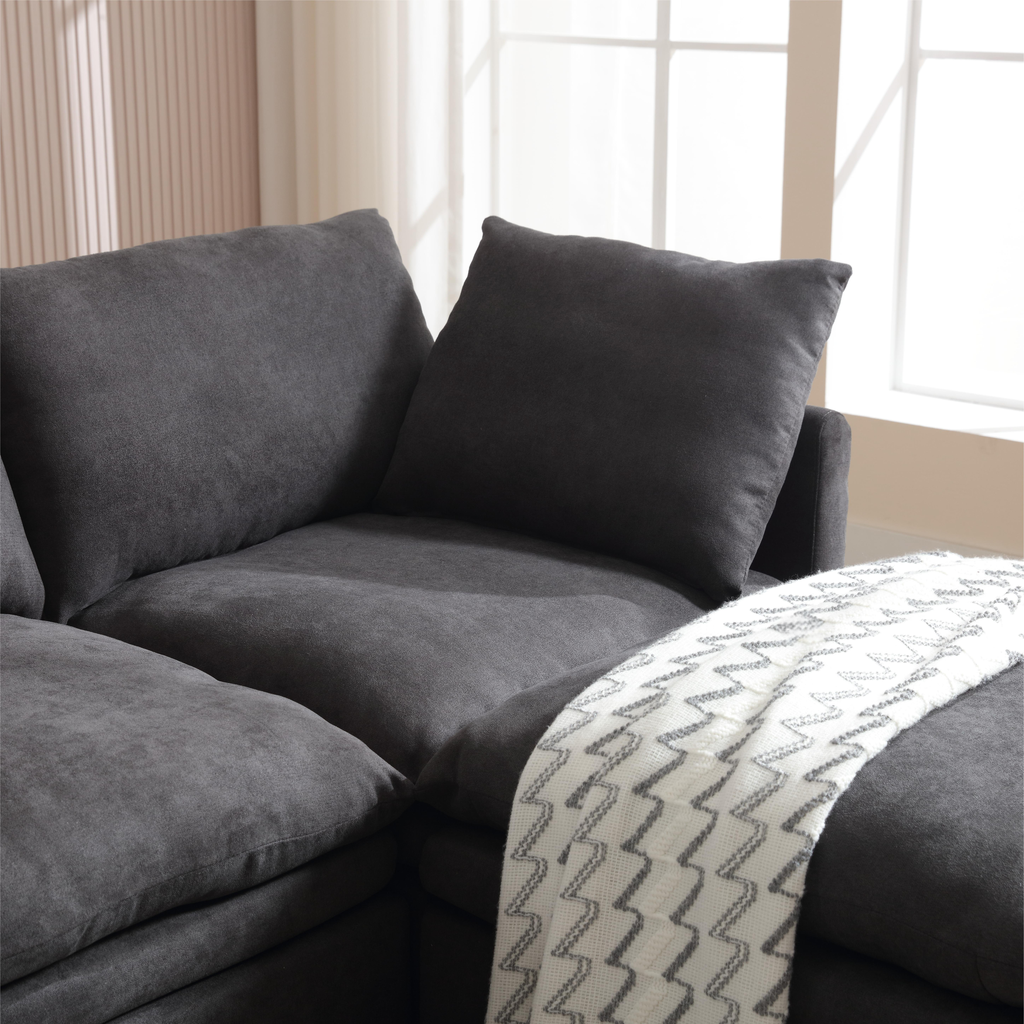 Plush dark gray sectional sofa with plush cushions and a patterned throw ideal for a modern living room