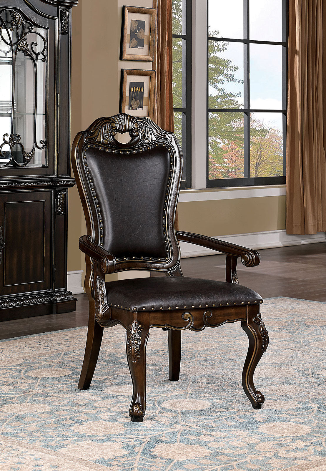 Ornate dark wood dining chair with deep brown leather upholstery and brass nailhead trim