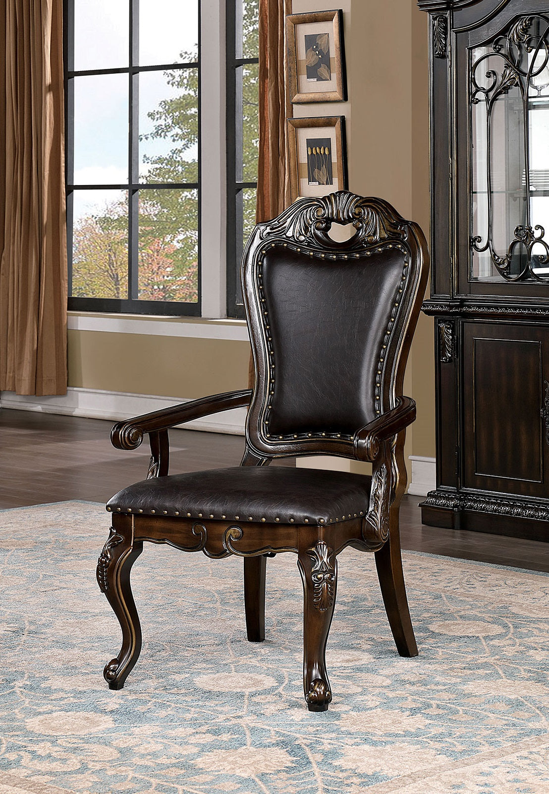 Ornate dark brown leather armchair with carved wood details and brass studs