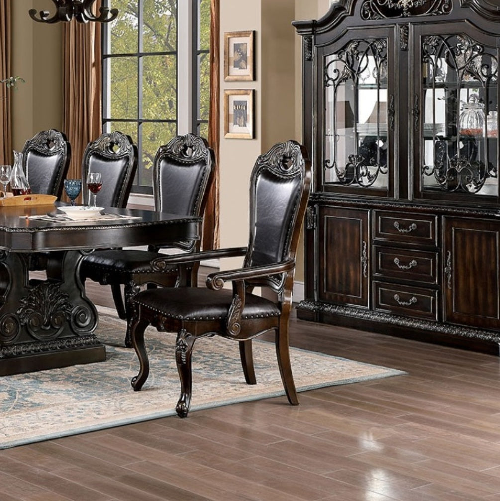 Dark wood dining table with carved pedestal base and upholstered chairs