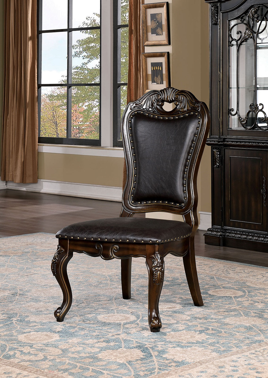 Ornate dark brown leather dining chair with carved wood legs and nailhead trim