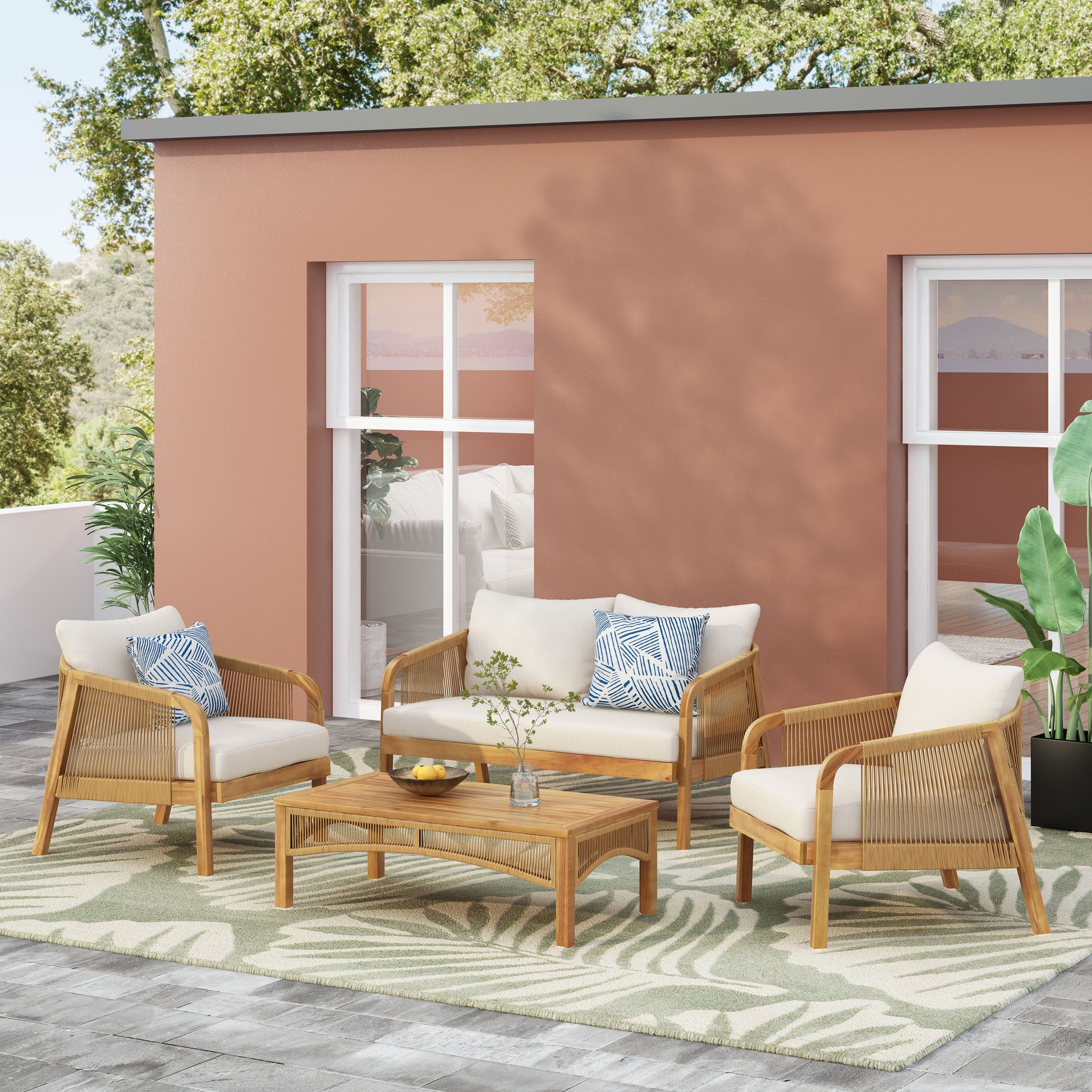 Woven rattan patio set with cream cushions and blue patterned pillows