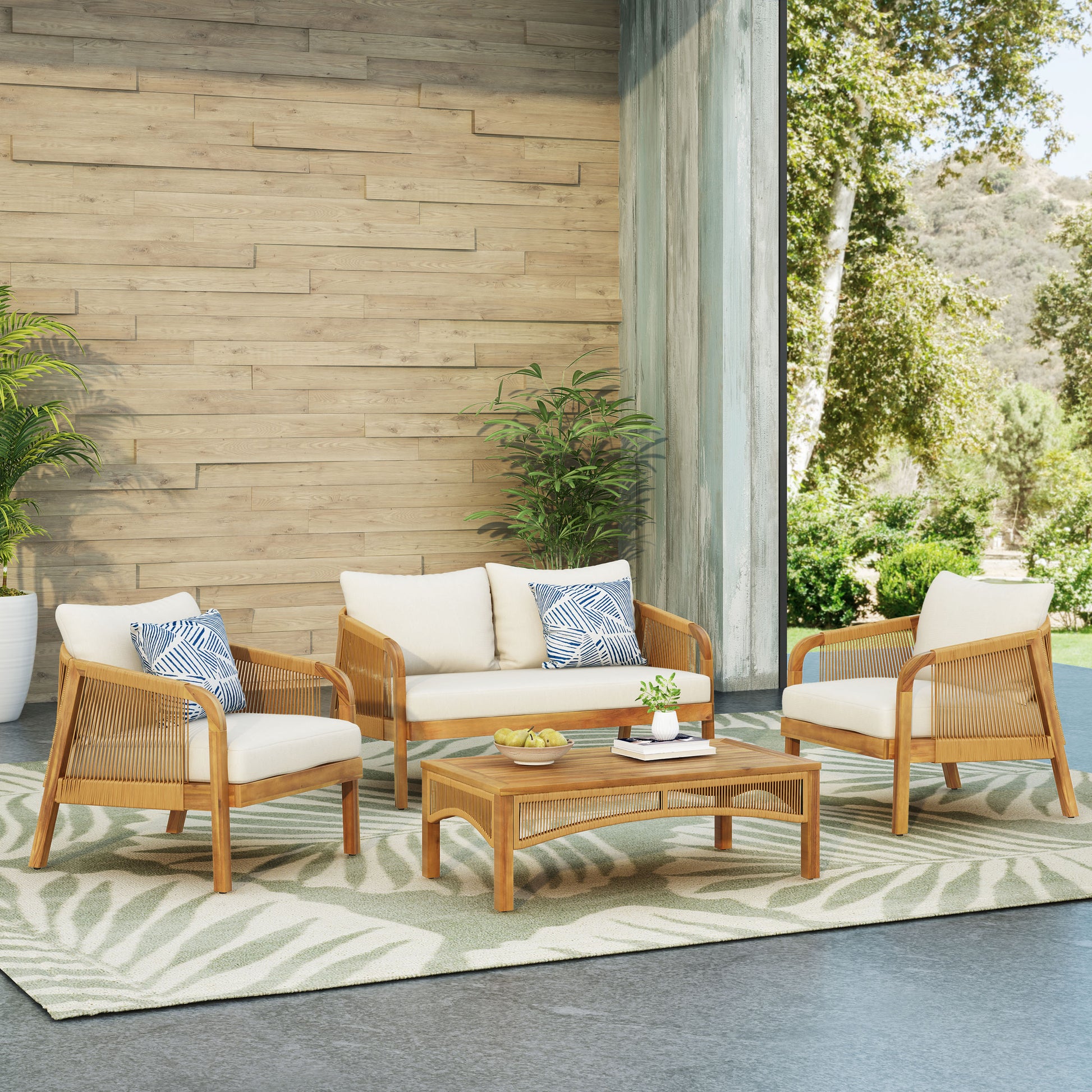 Rattan and wood outdoor sofa set with cream cushions and blue patterned pillows