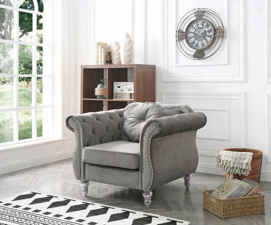 Tufted grey velvet armchair with silver nailhead trim and decorative round pillow