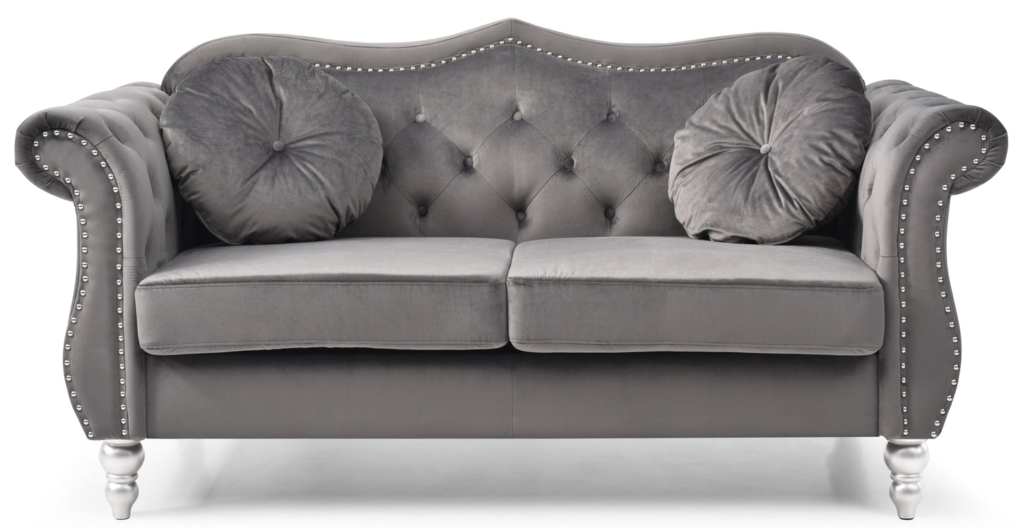Tufted grey velvet loveseat with silver nailhead trim and two round accent pillows