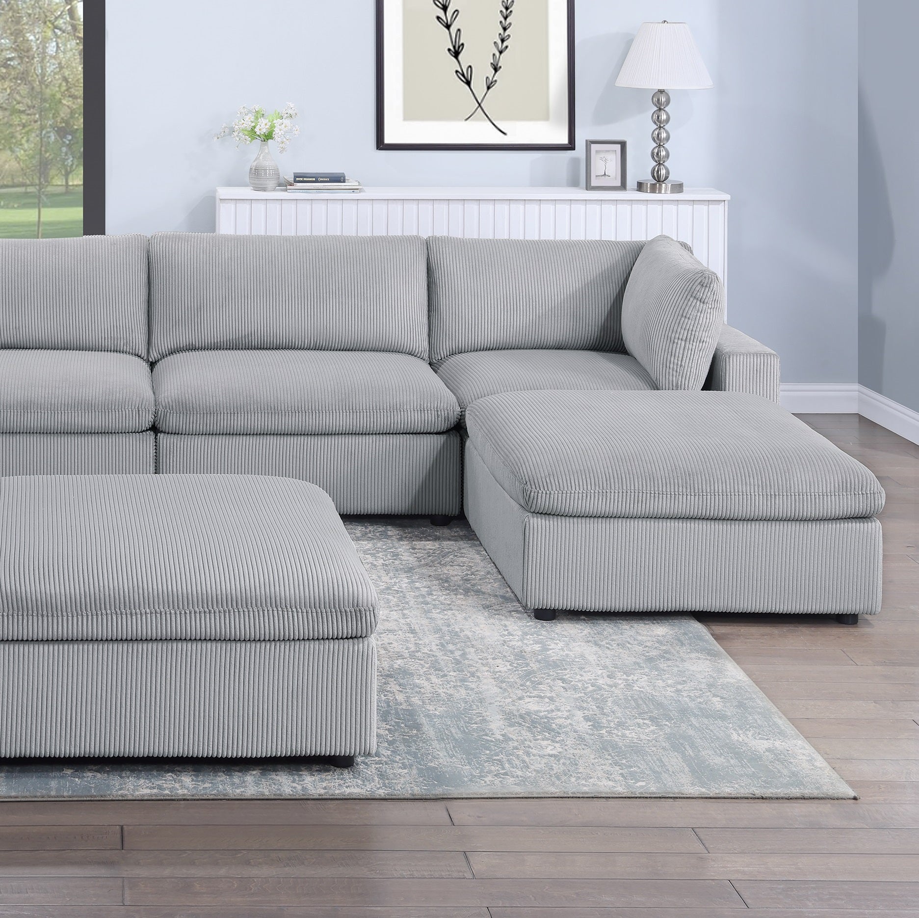 Comfortable gray corduroy sectional sofa with modular ottoman in a living room setting
