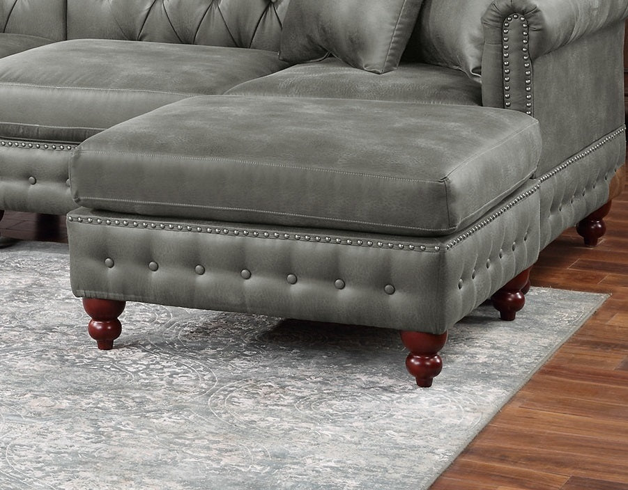 Grey tufted leather ottoman with silver nailhead trim and mahogany legs