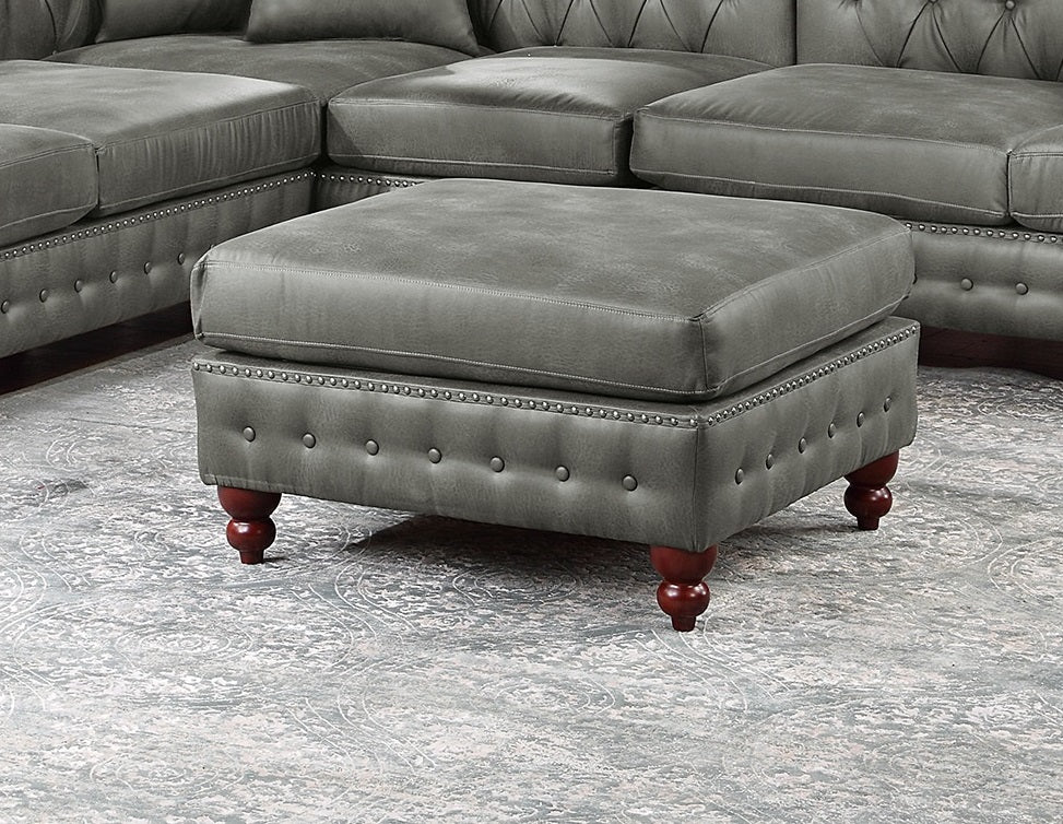 Grey tufted leather ottoman with silver nailhead trim and dark wood legs
