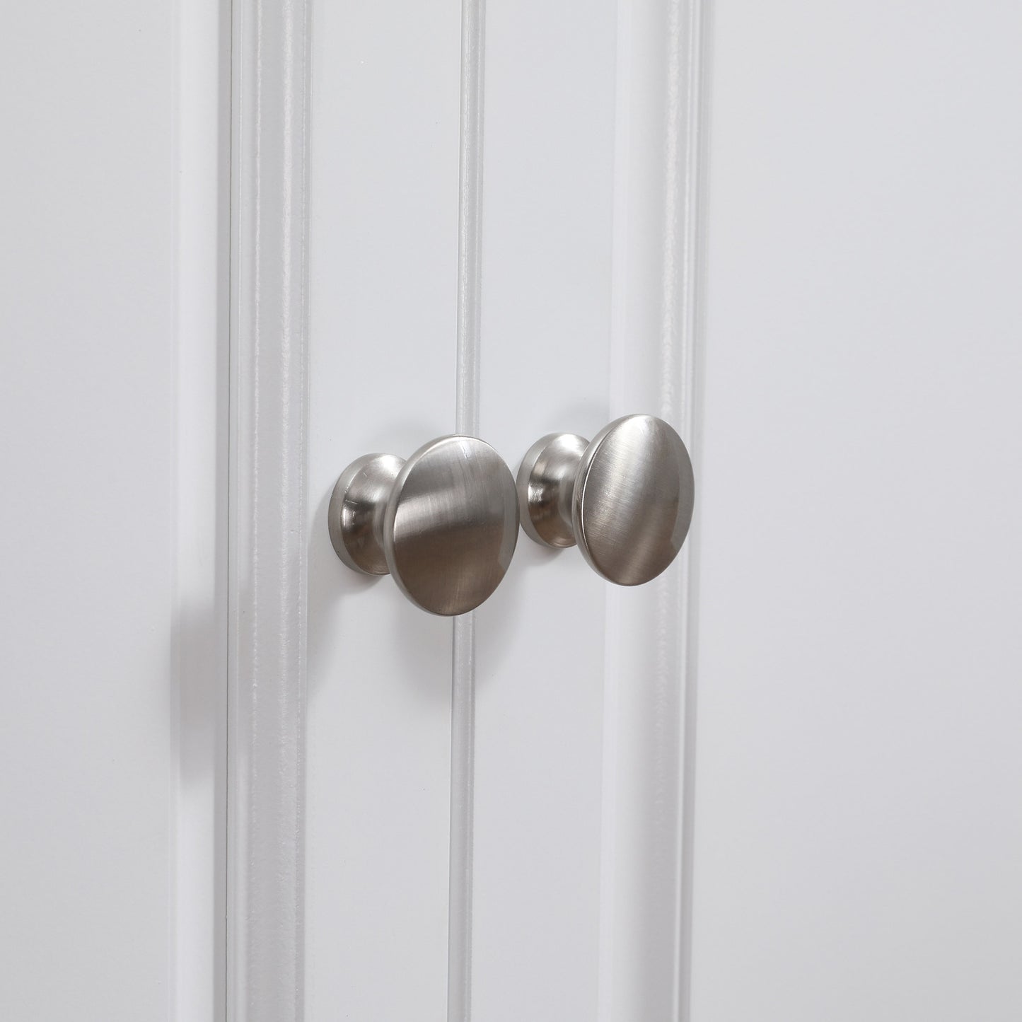 Brushed nickel cabinet knobs with a brushed finish on a white paneled door
