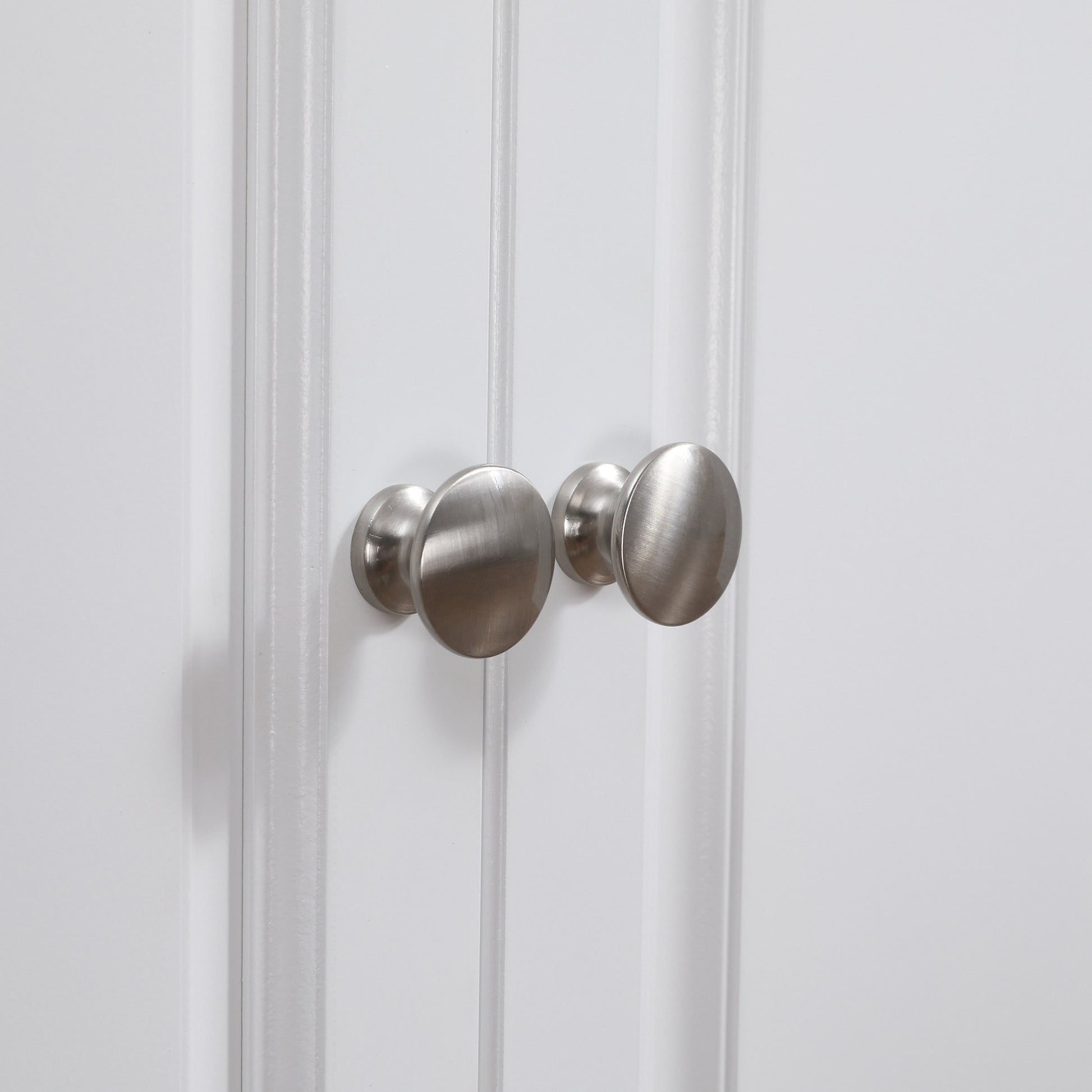 Brushed nickel cabinet knobs with a brushed finish on a white paneled door