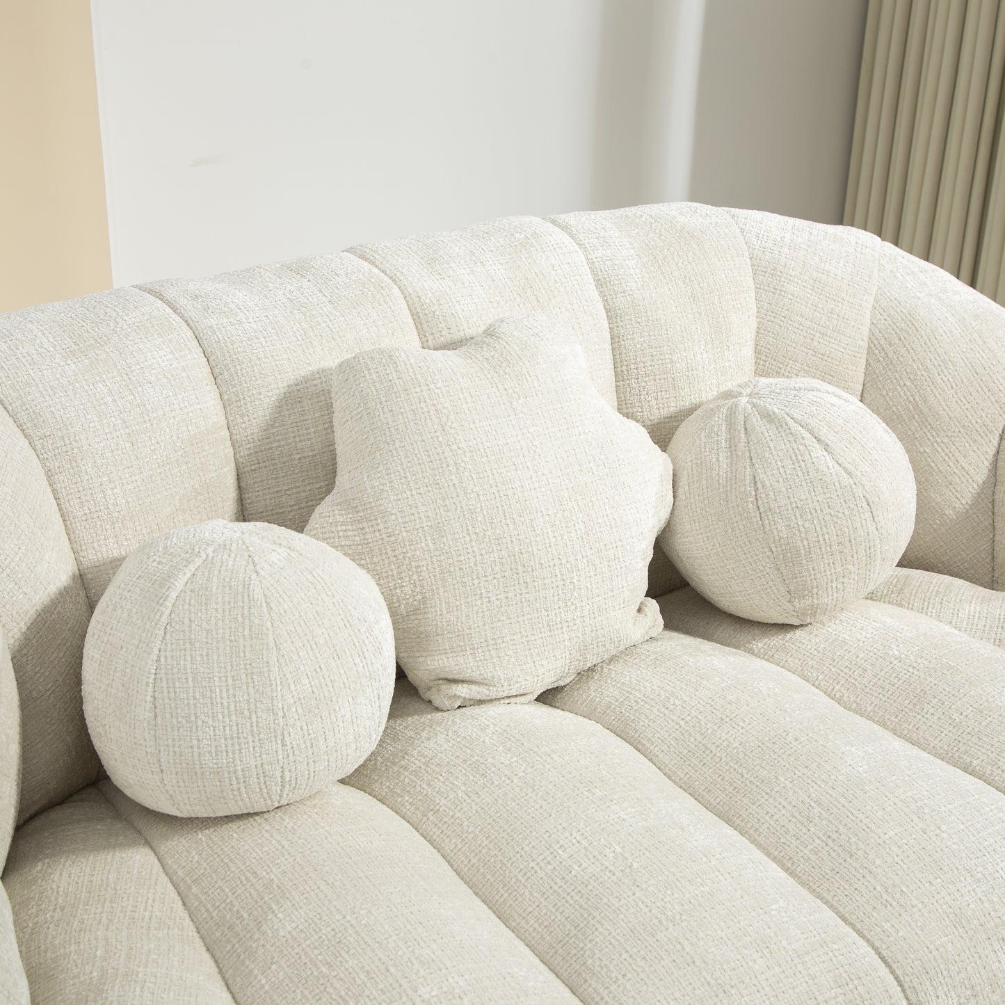 Cream textured fabric sofa with three decorative throw pillows two round and one starshaped