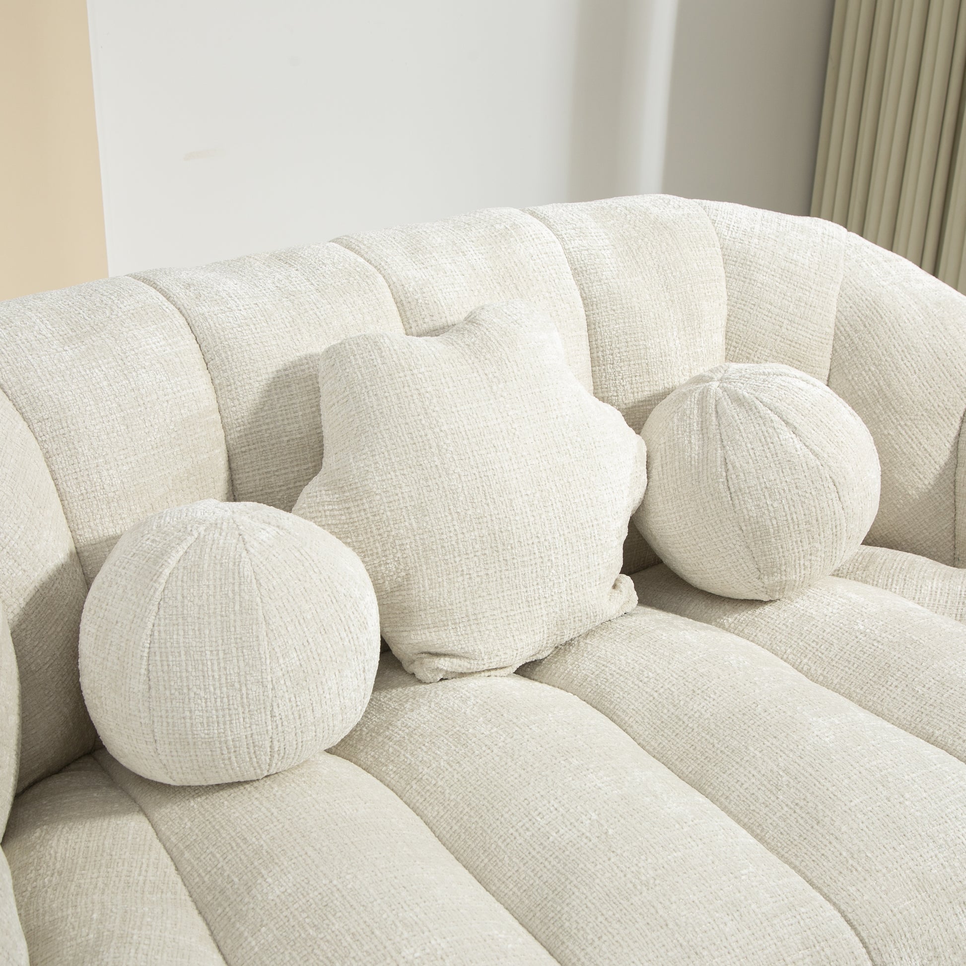 Cream textured fabric sofa with three decorative throw pillows two round and one starshaped