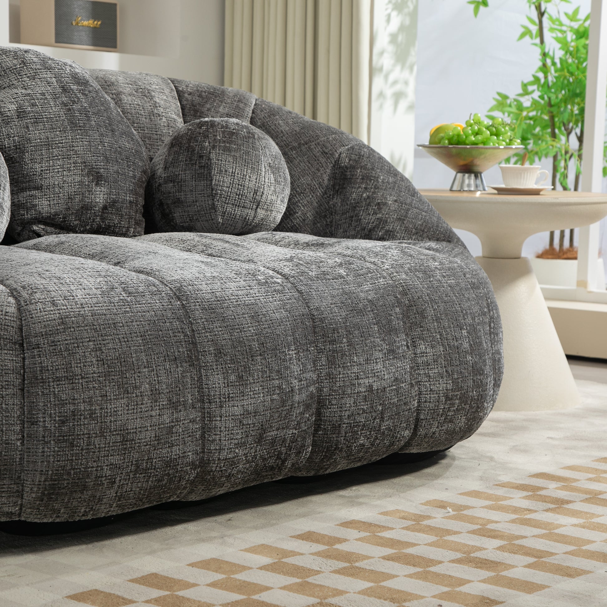 Deep charcoal textured fabric sofa with plush rounded cushions and a matching bolster pillow