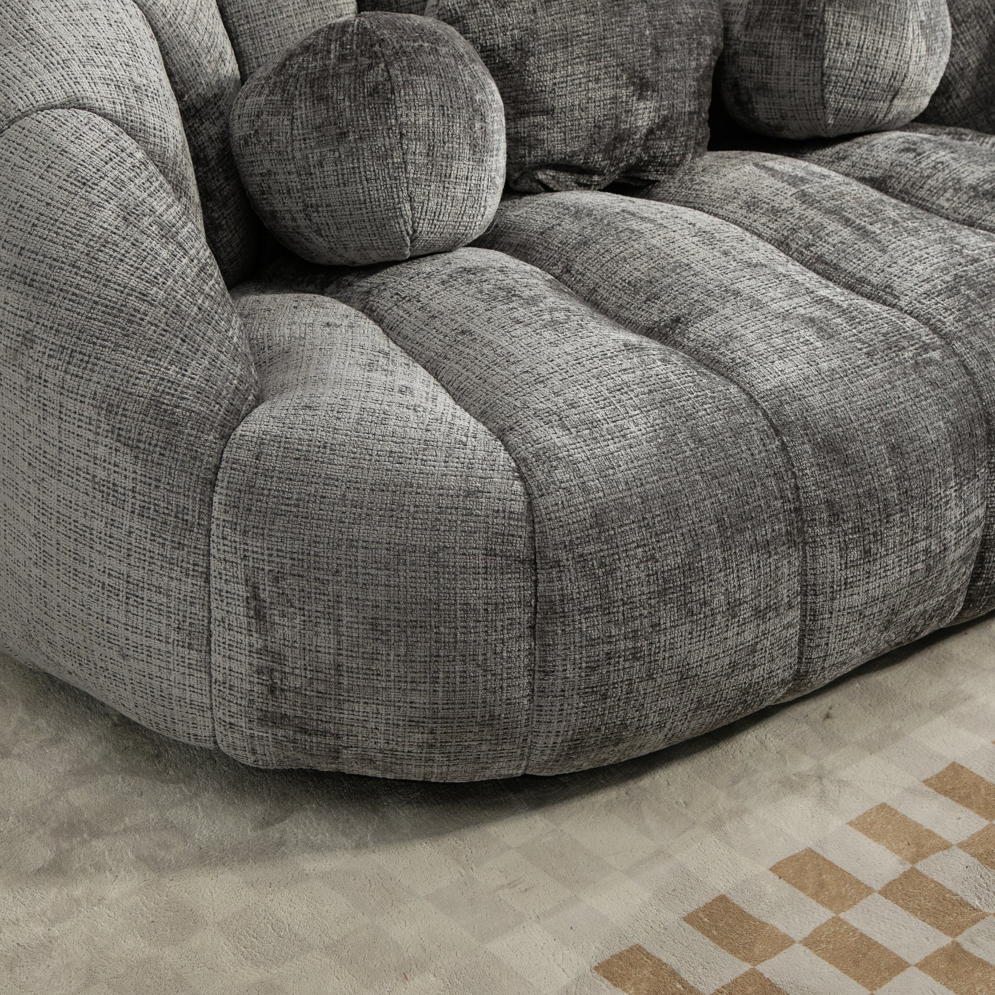 Plush grey velvet sofa with rounded armrests and textured cushions designed for ultimate comfort