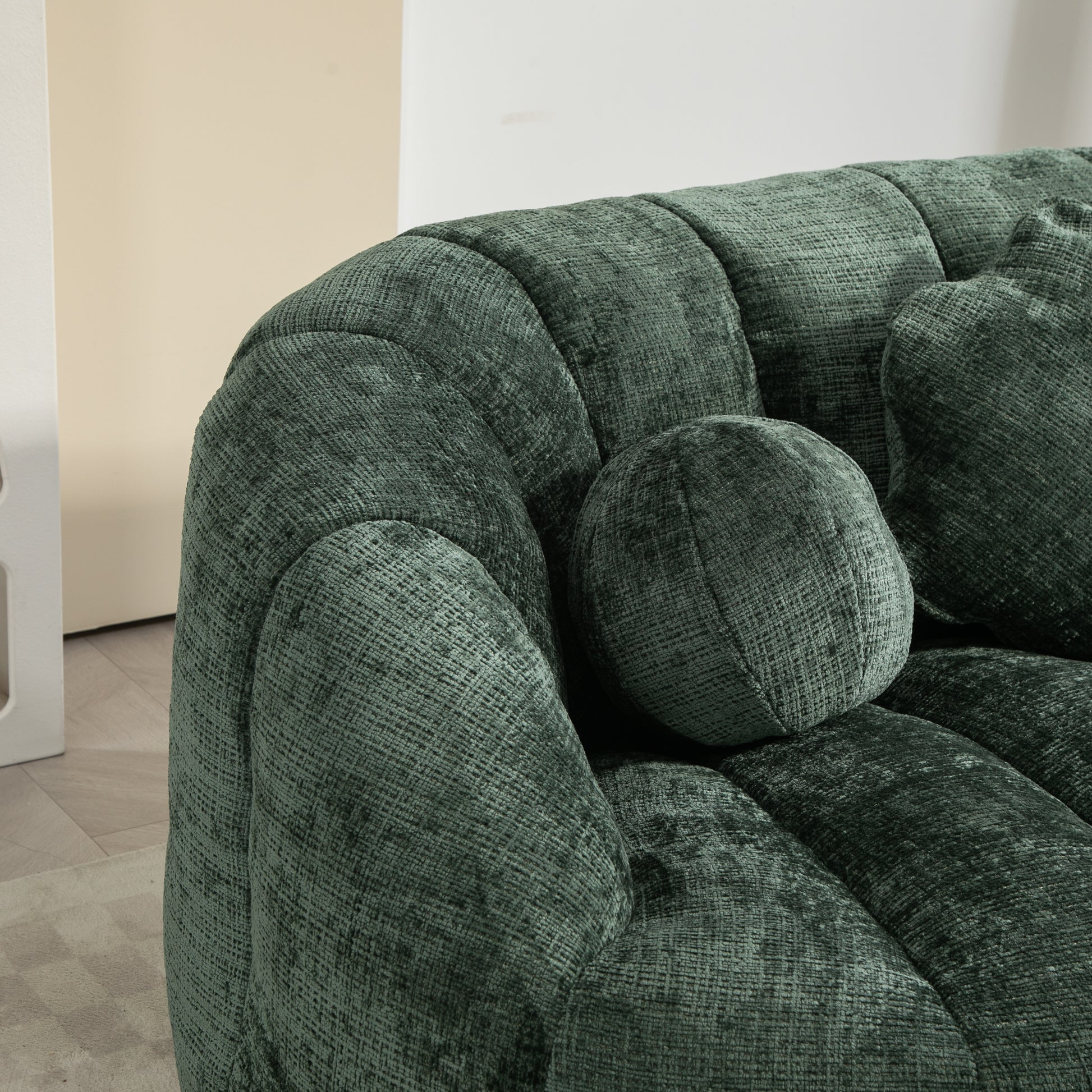 Emerald green velvet sofa with channel tufting and round accent pillow