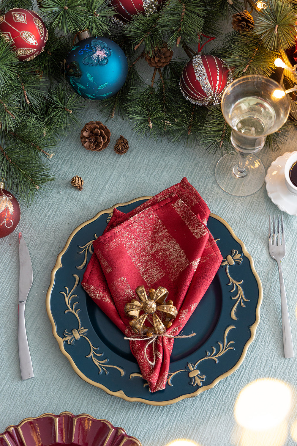Red and gold plaid cloth napkin with a golden bow napkin ring on a dark blue plate