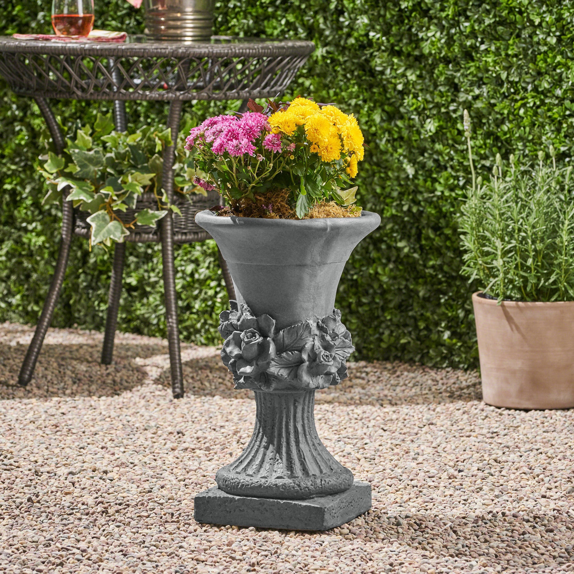 Ornate grey stone planter with rose embellishments perfect for outdoor garden decor