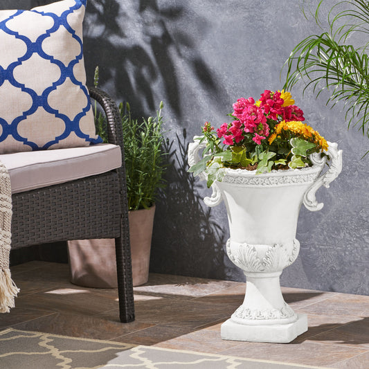 White ornate garden planter overflowing with vibrant pink and yellow flowers and greenery