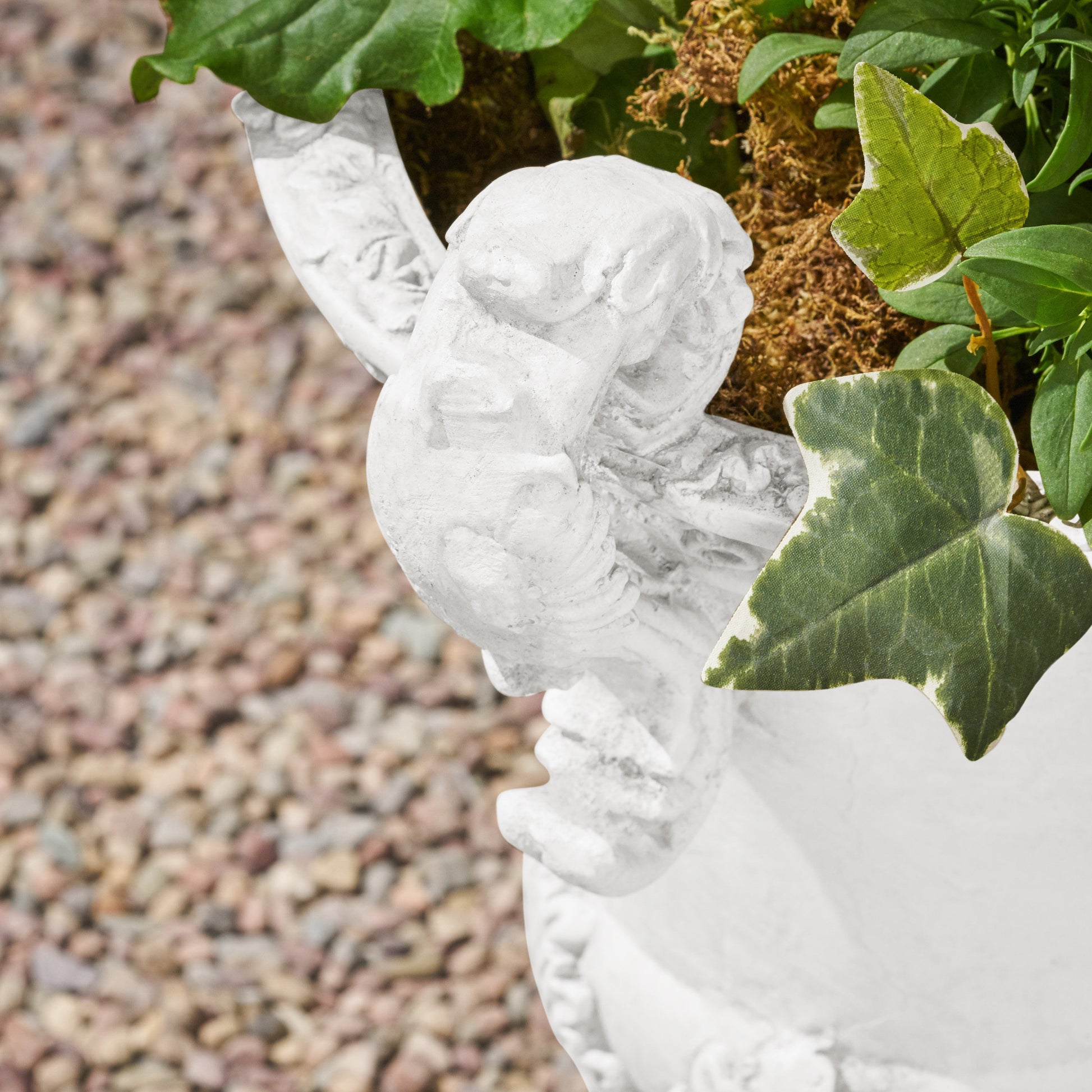 White stone cherub planter with green ivy and moss accents