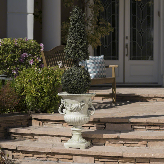 Stone urn with sculpted roses and handles holding a topiary plant