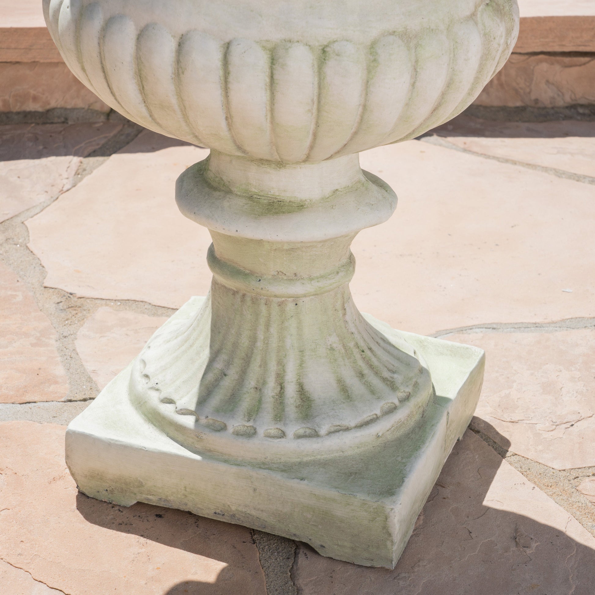 Weathered white concrete garden urn with fluted detailing for outdoor decor