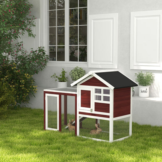Red and white wooden rabbit hutch with two rabbits inside backyard setting