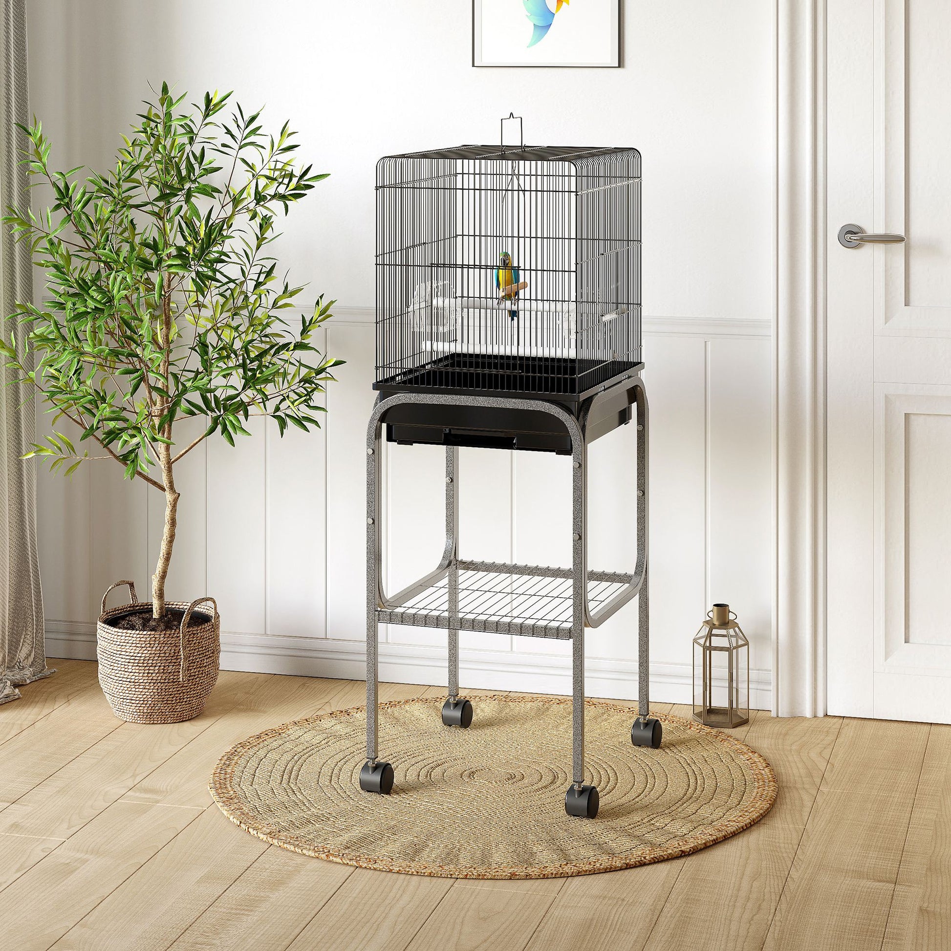 Black wire bird cage with a perch for small birds on a grey rolling stand