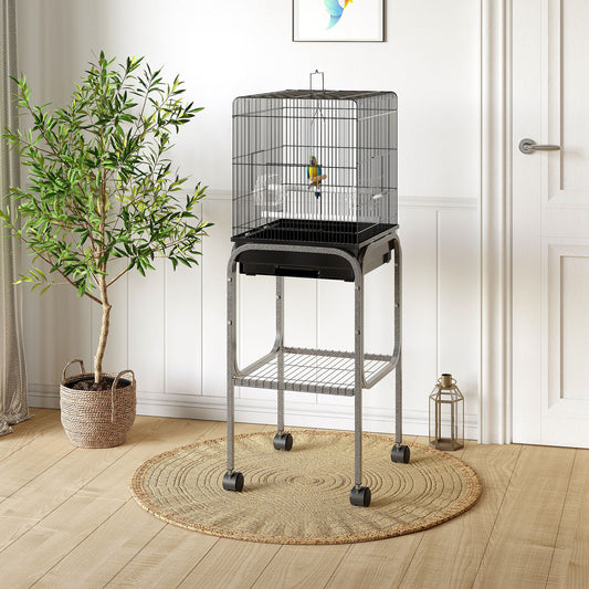 Black wire bird cage with a perch for small birds on a grey rolling stand
