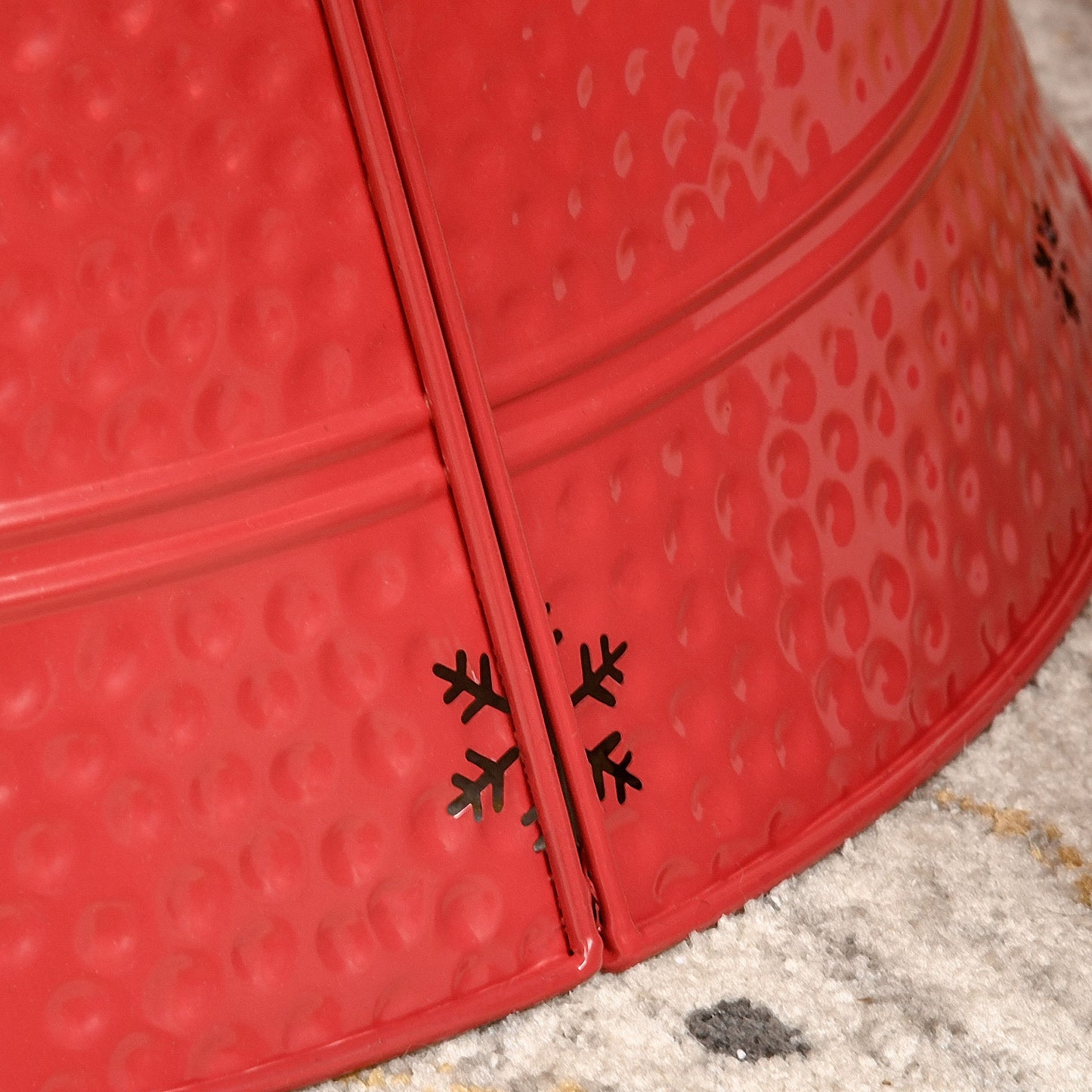 Closeup of red metal Christmas tree skirt with embossed snowflake cutouts