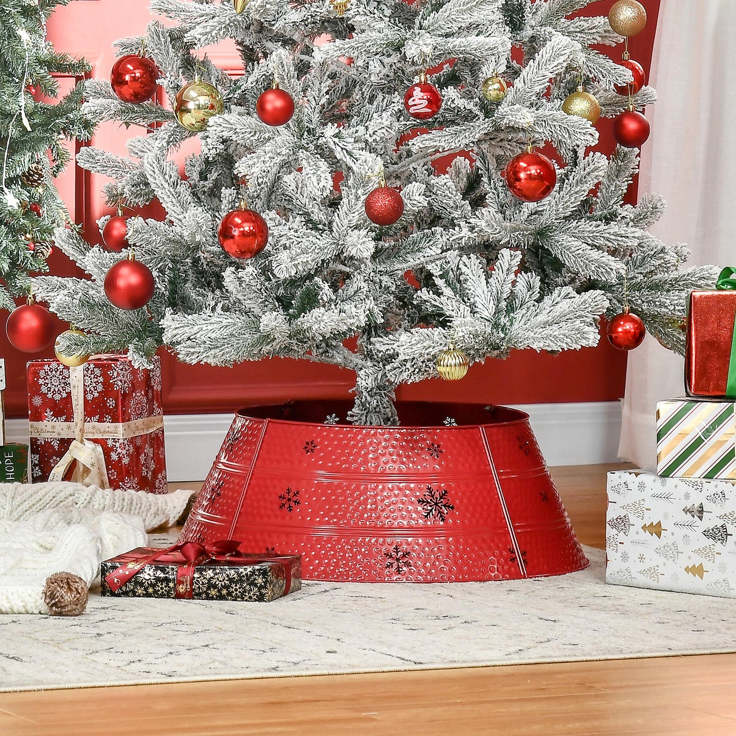 Flocked artificial Christmas tree with red and gold ornaments and a festive red tree collar